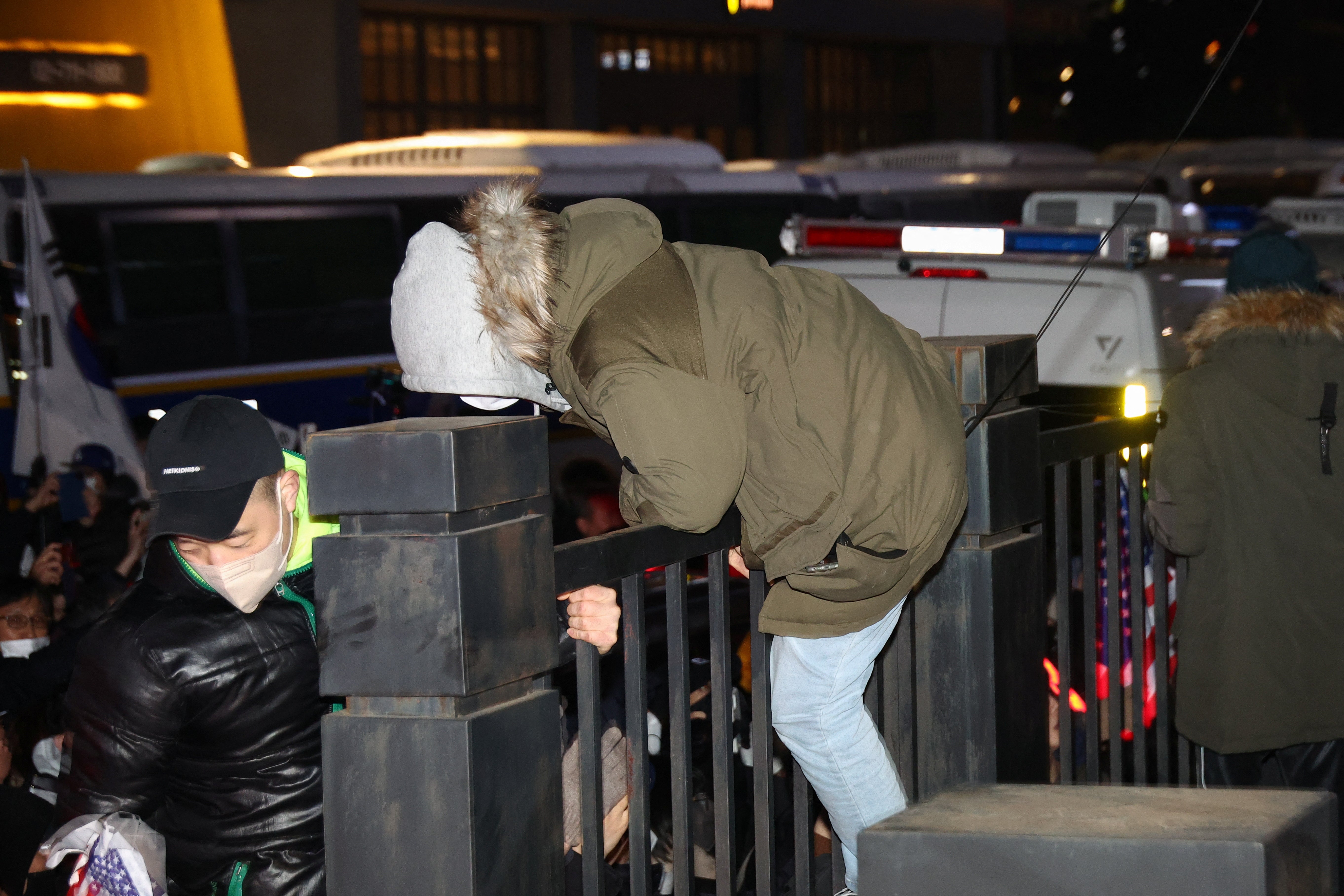 A protester jumps over a fence at the court during a rally