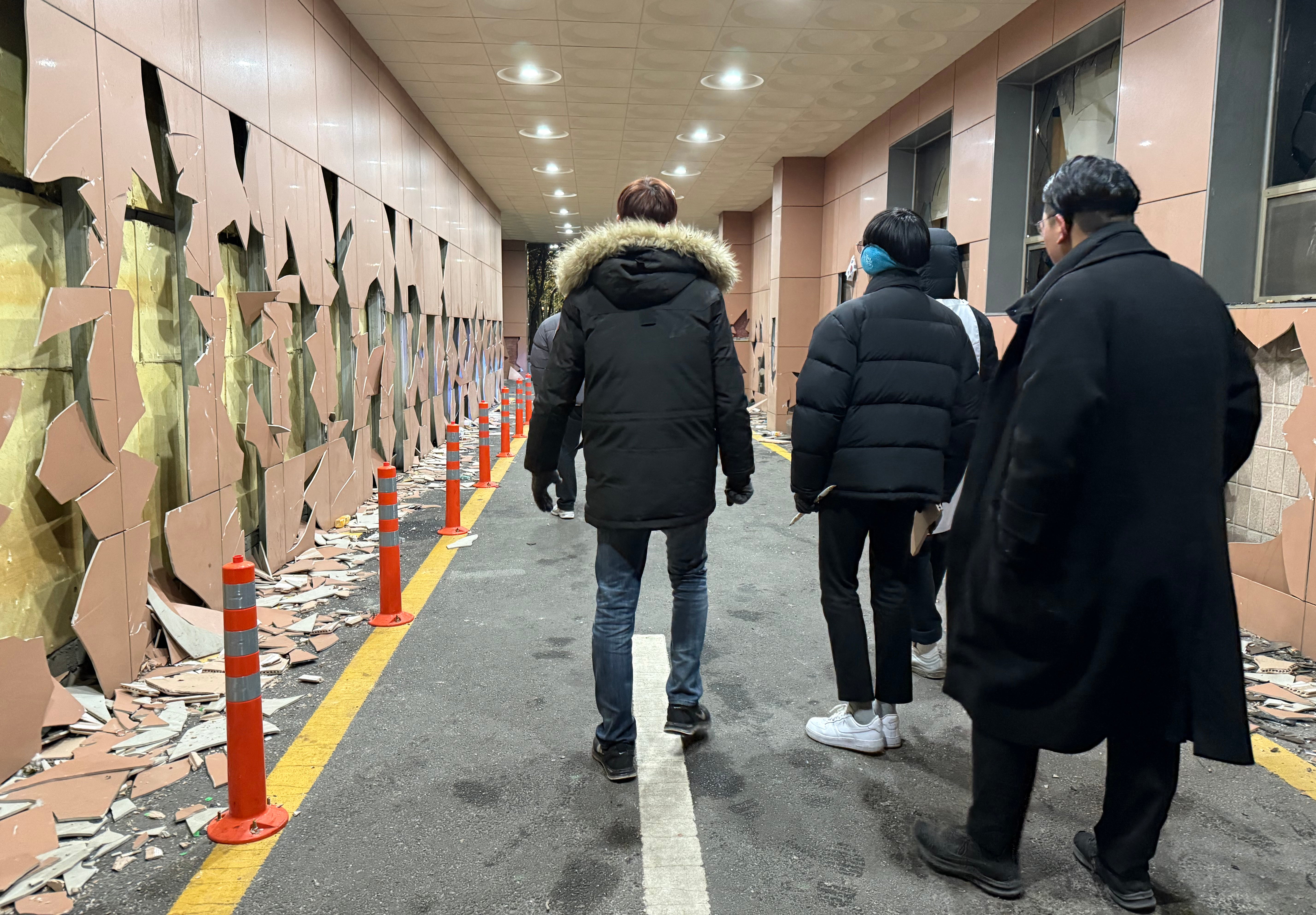 Supporters of Yoon Suk Yeol walk past the destroyed wall at the Seoul Western District Court