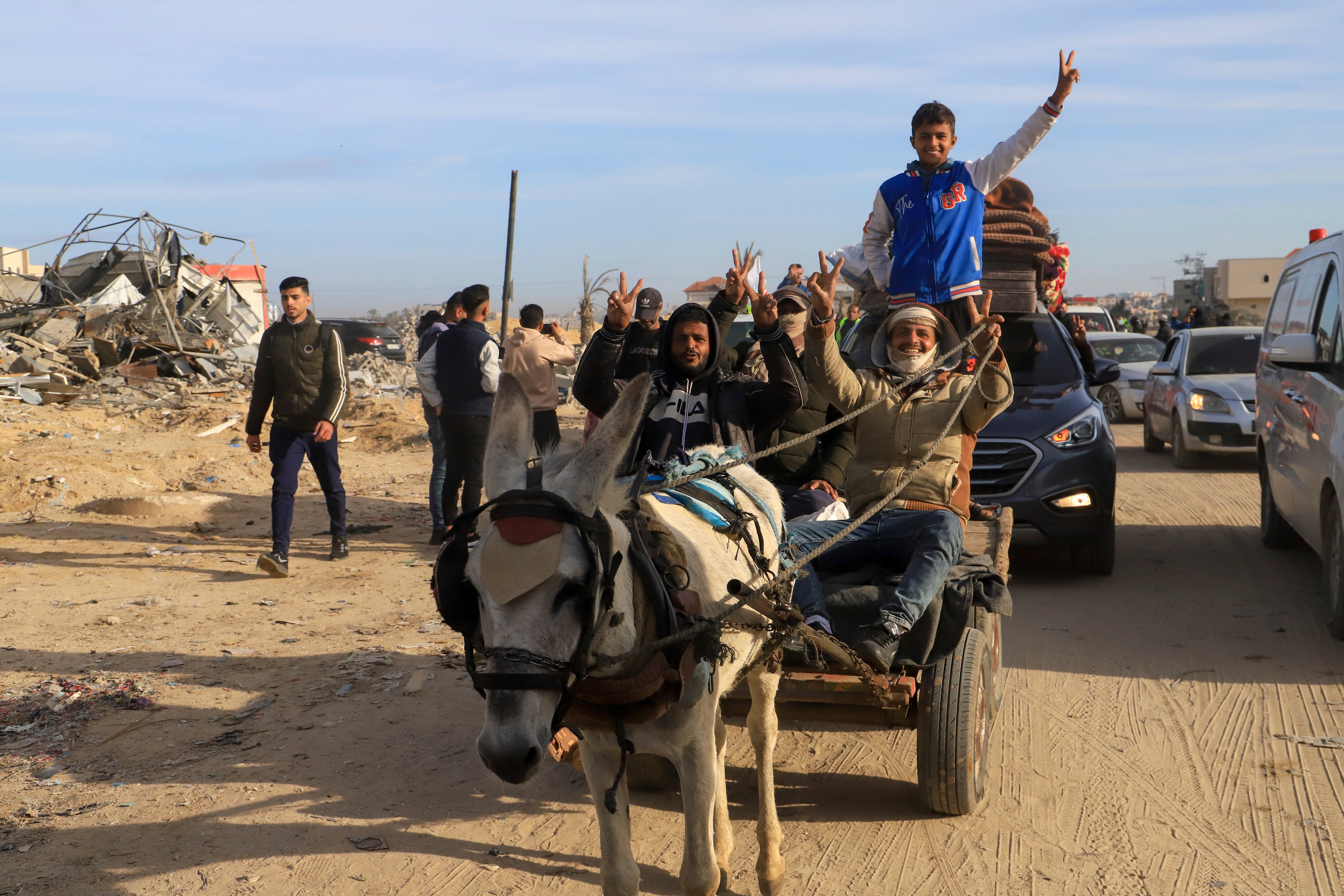 Displaced Palestinians flash V-sign as they return to Rafah