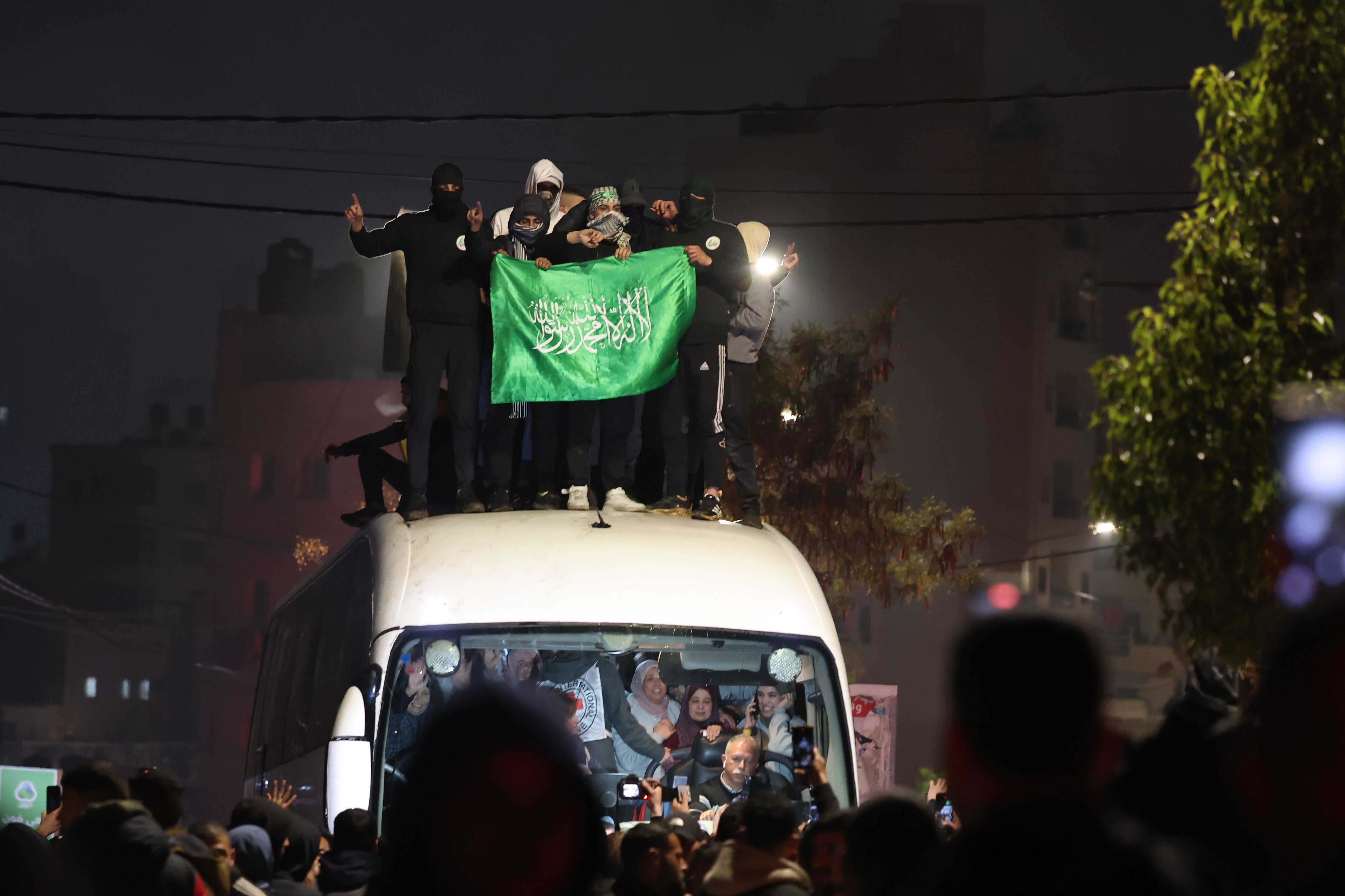 People are seen on top a bus carrying released Palestinian prisoners from the Ofer Israeli military prison as it arrives in Ramallah, early 20 January 2025