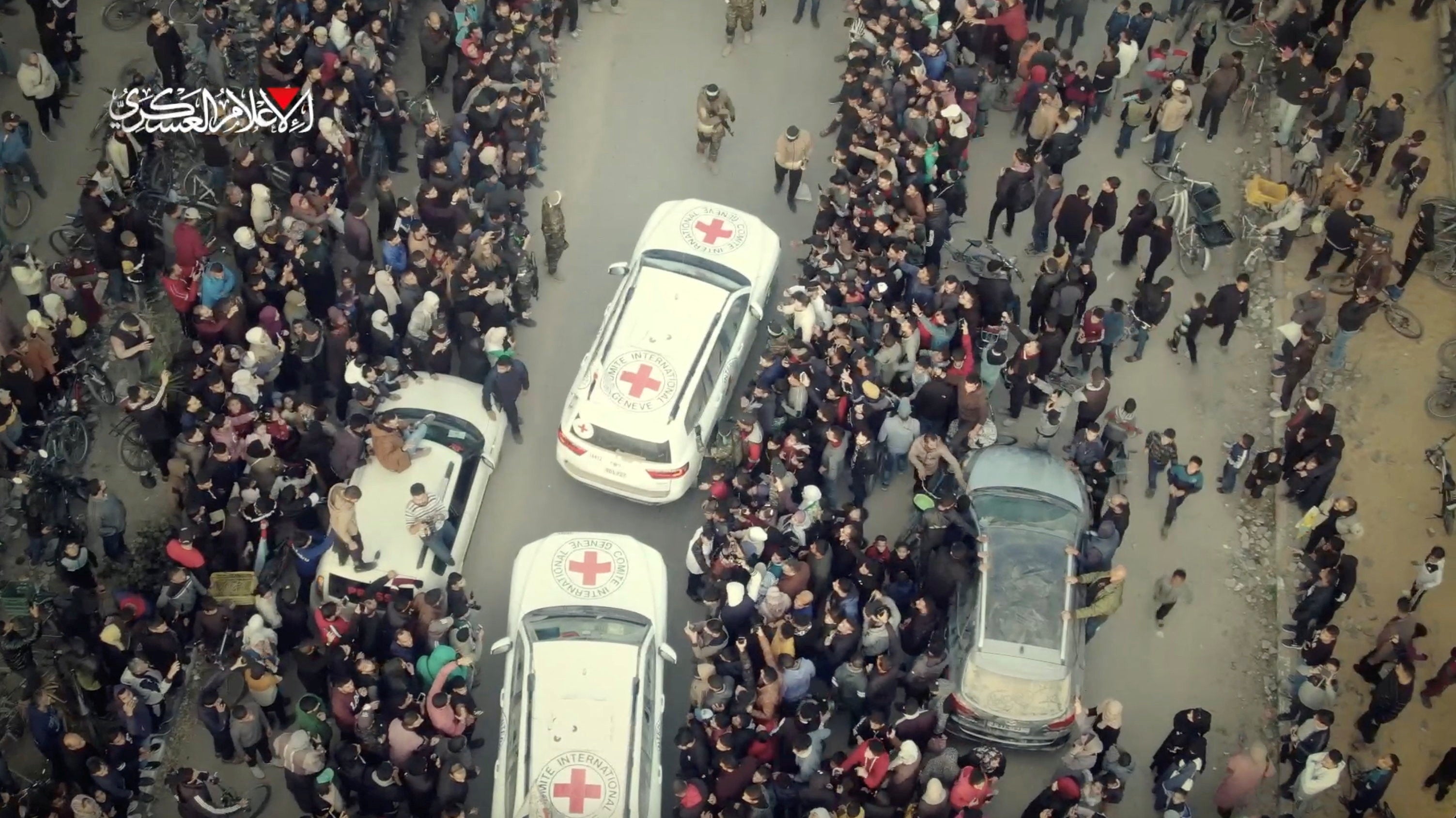 People gather near vehicles as Romi Gonen, Doron Steinbrecher and Emily Damari, three hostages who have been held in Gaza since the deadly 7 October 2023 attack, are released