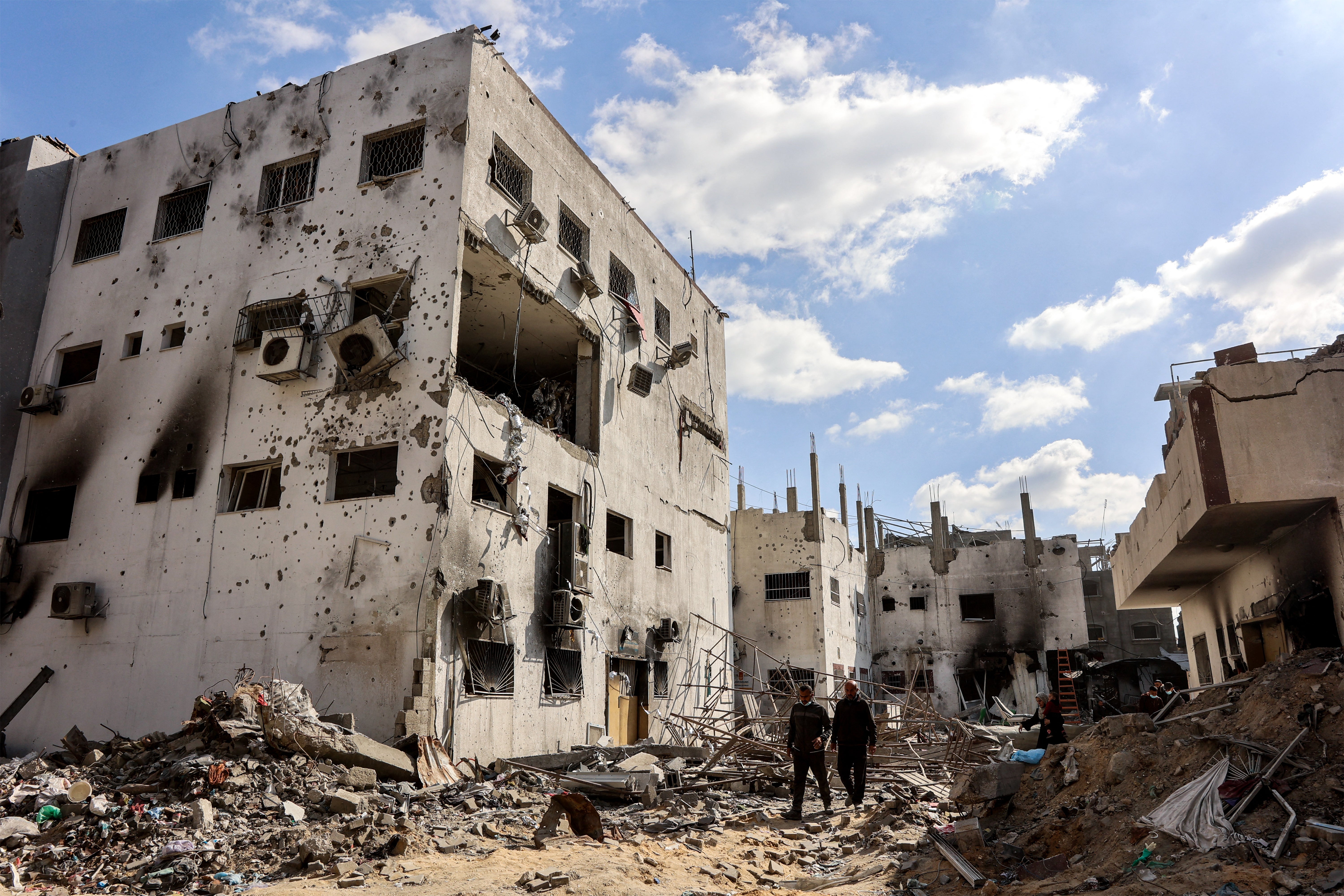 People walk by the destroyed remains of Kamal Adwan hospital in Beit Lahia