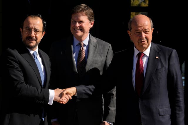 <p>Republic of Cyprus president Nikos Christodoulides  shakes hands with Ersin Tatar, the president of unrecognised breakaway Turkish Republic of Northern Cyprus with a UN representative in between</p>