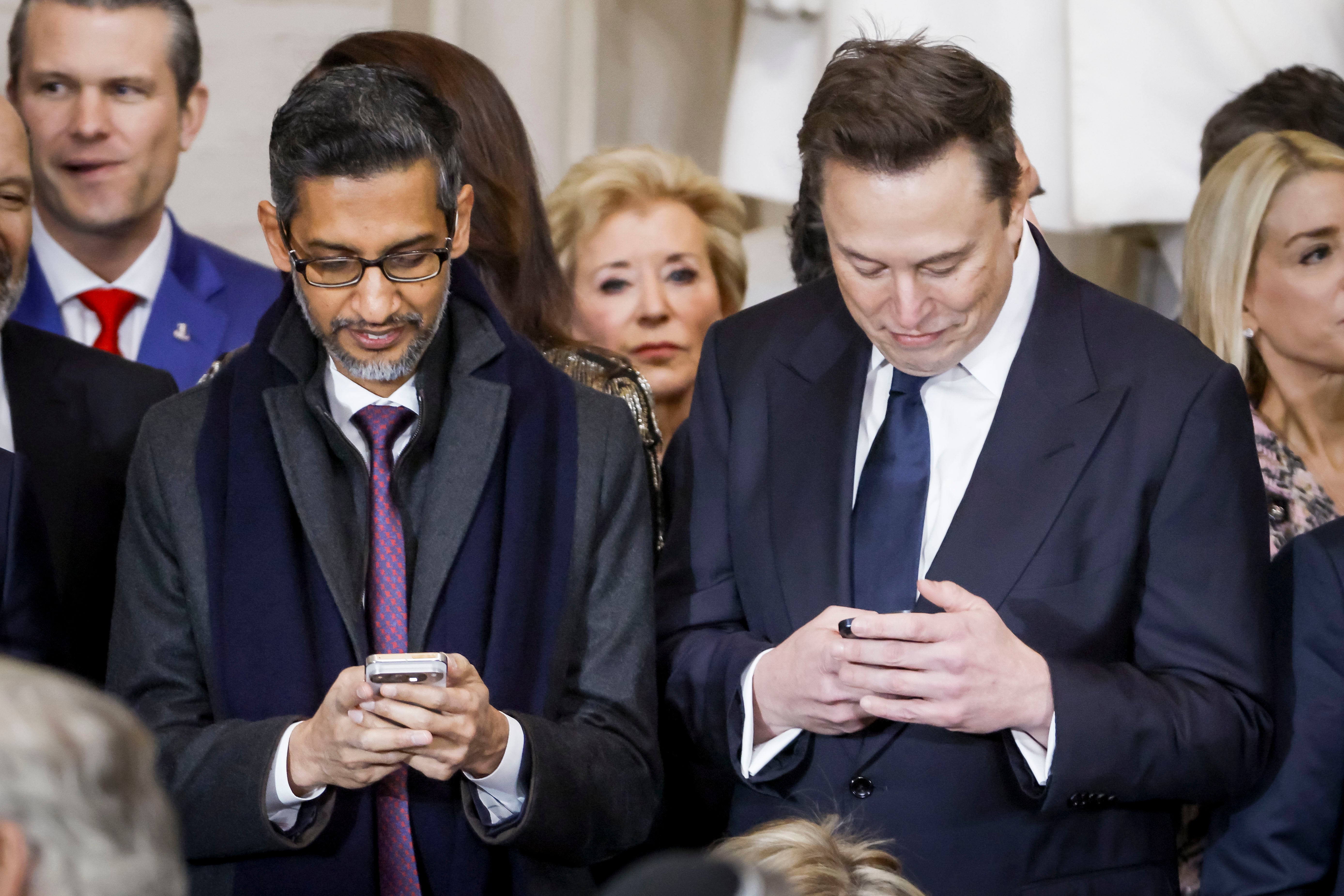 Alphabet CEO Sundar Pichai, left, and Elon Musk check their phones