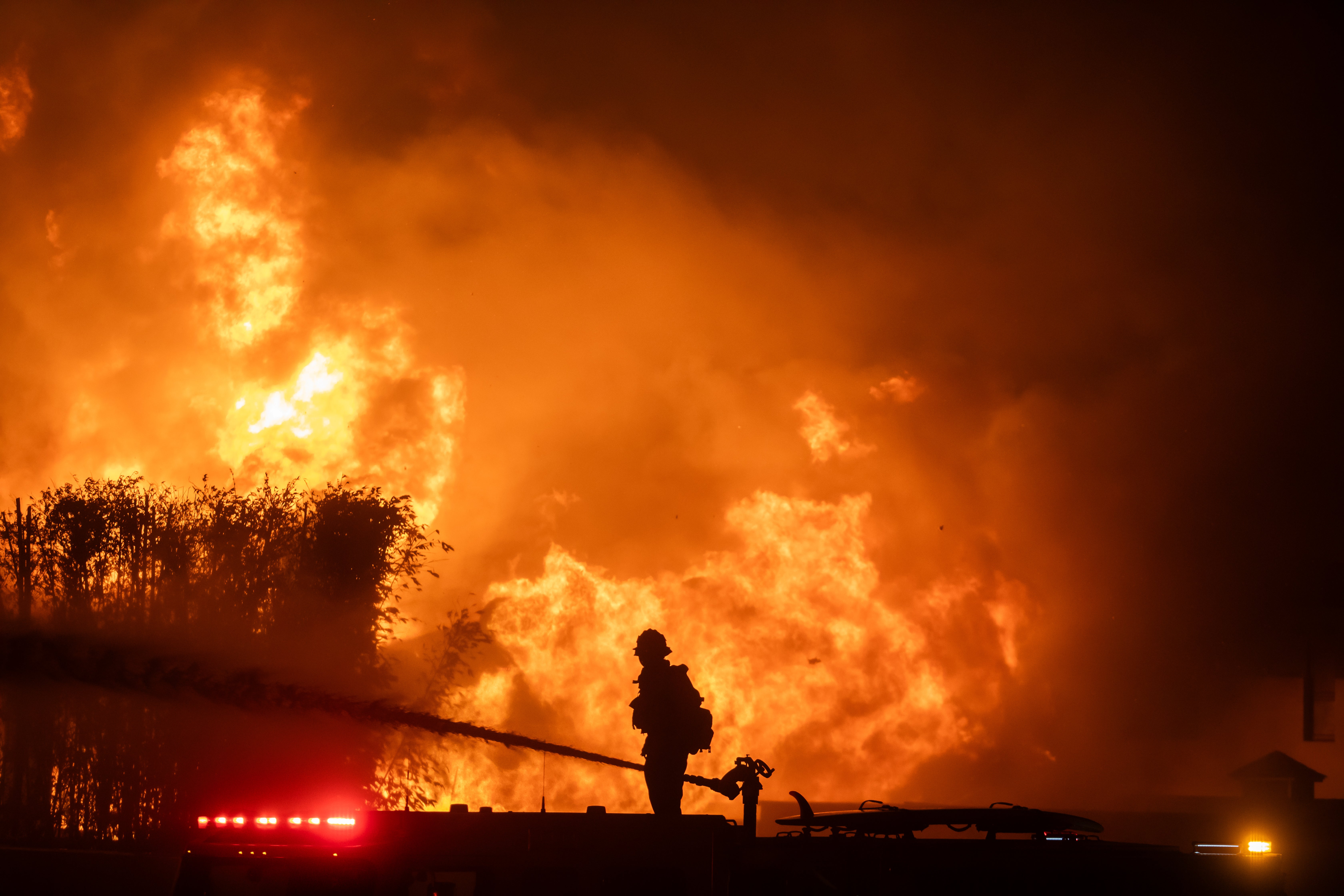 A firefighter stands on top of a fire truck to battle the Palisades Fire amid a powerful windstorm earlier this month in Los Angeles, California. Another Santa Ana wind event was forecast this week in Los Angeles County