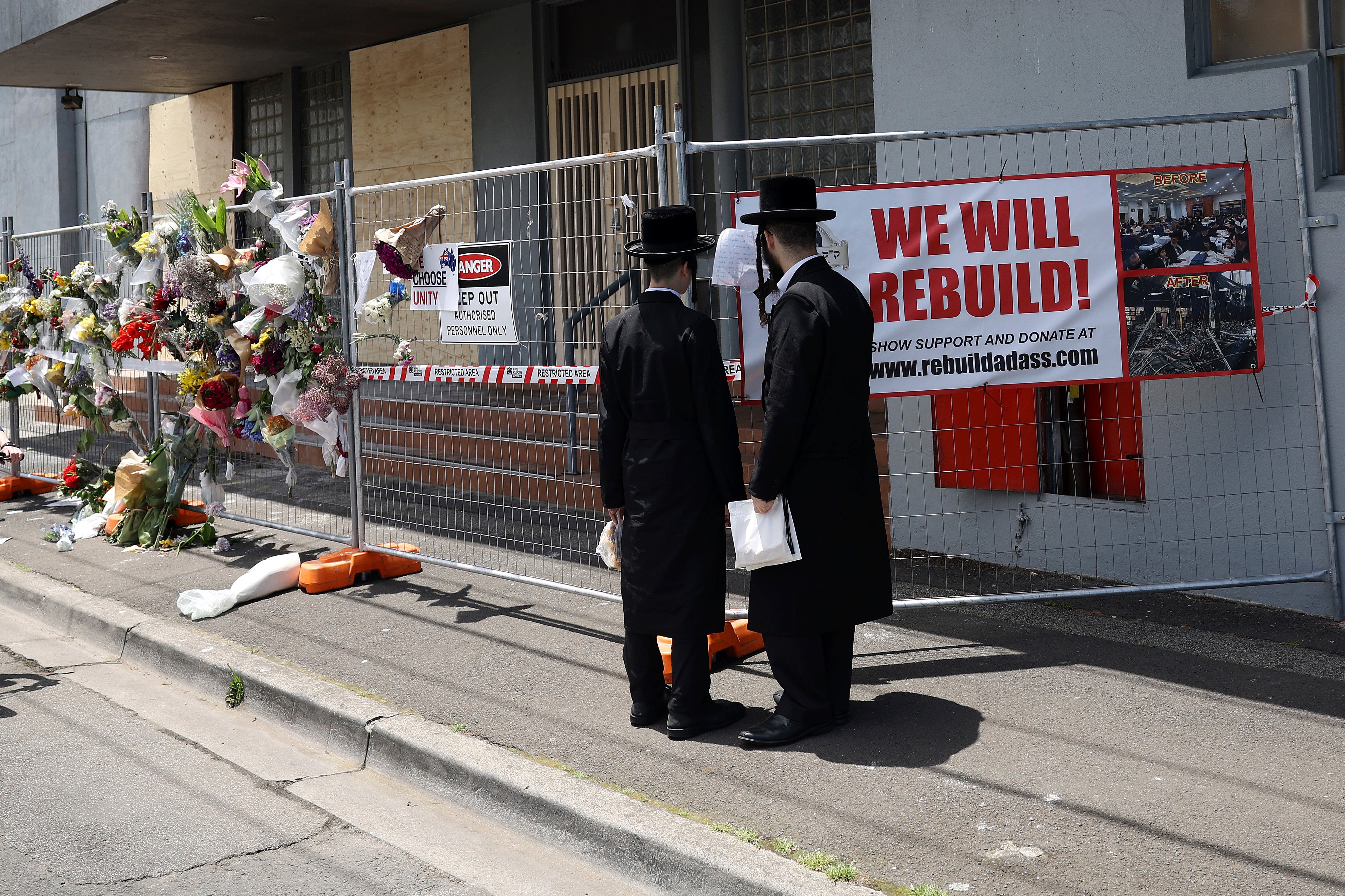 Men stand outside the Adass Israel Synagogue after a firebombing in Melbourne, Australia, last month