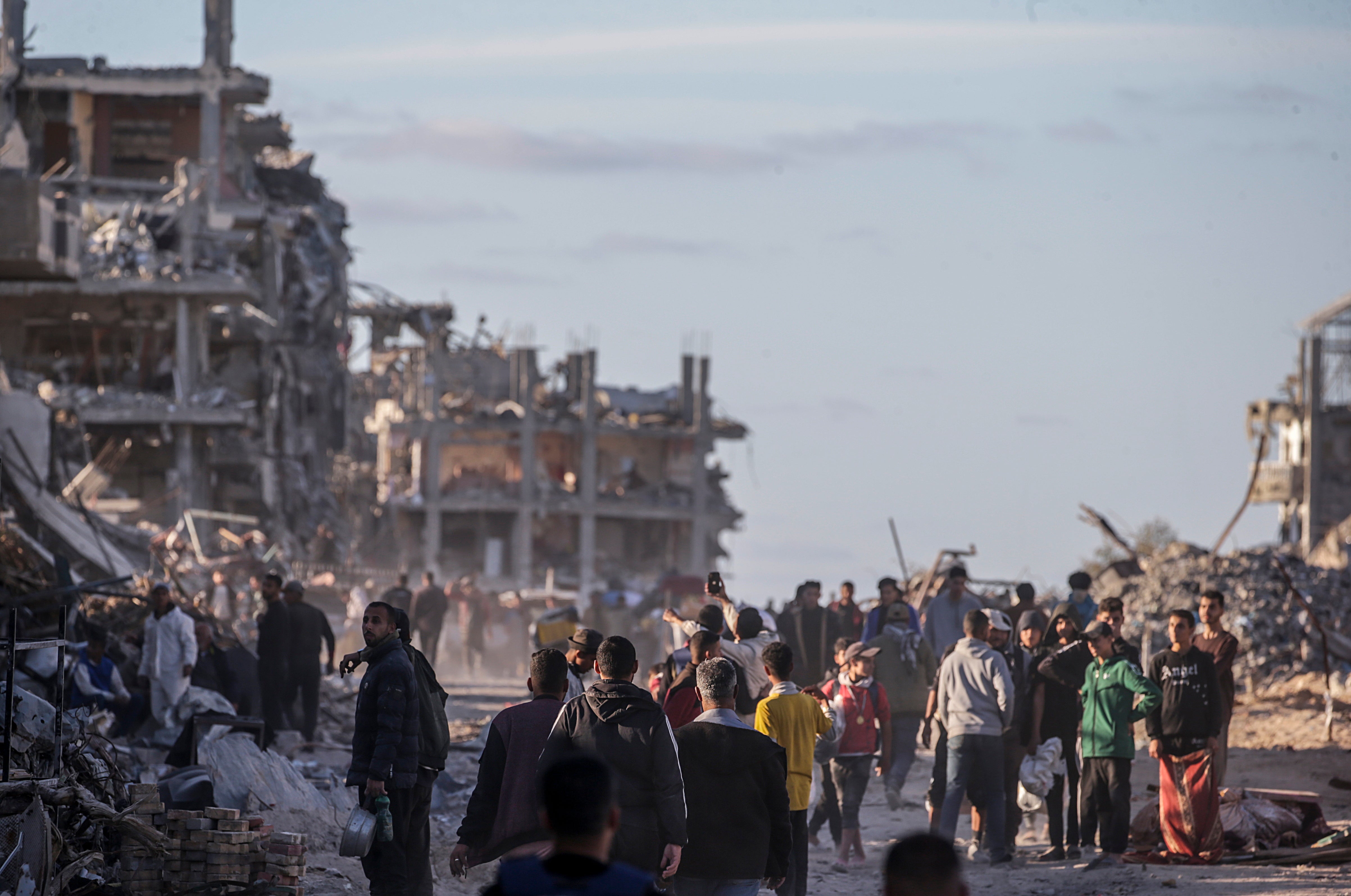 Internally displaced Palestinians walk along a street among the rubble of destroyed buildings amid a ceasefire between Israel and Hamas, in Rafah, southern Gaza Strip, 20 January 2025