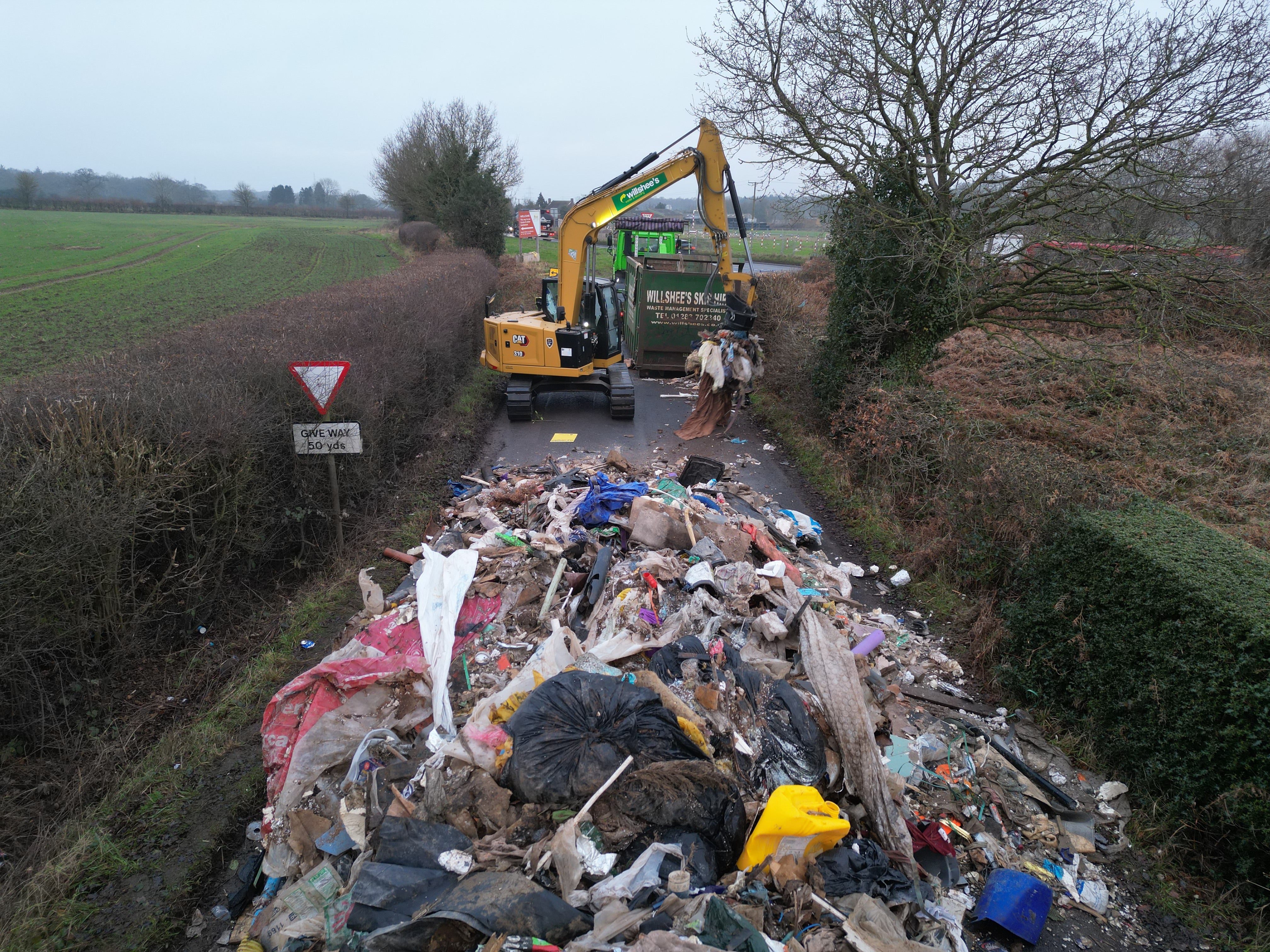 <p>Contractors work to remove the ten-ft-high pile of waste from Watery Lane, on the outskirts of Lichfield in Staffordshire</p>