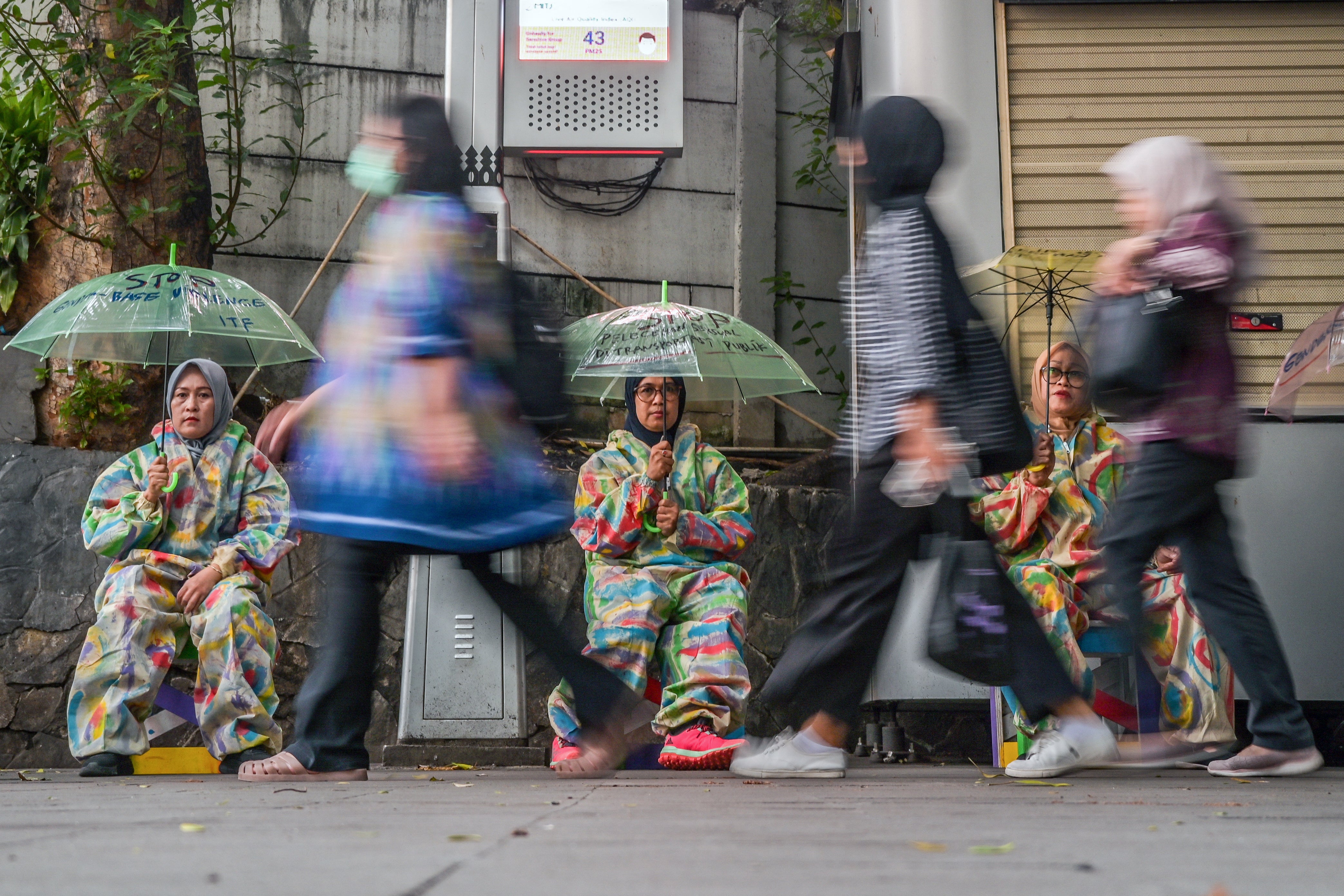 <p>Pedestrians walk past activists taking part in a sit-in to raise awareness on gender-based violence in Jakarta on 10 December 2024</p>