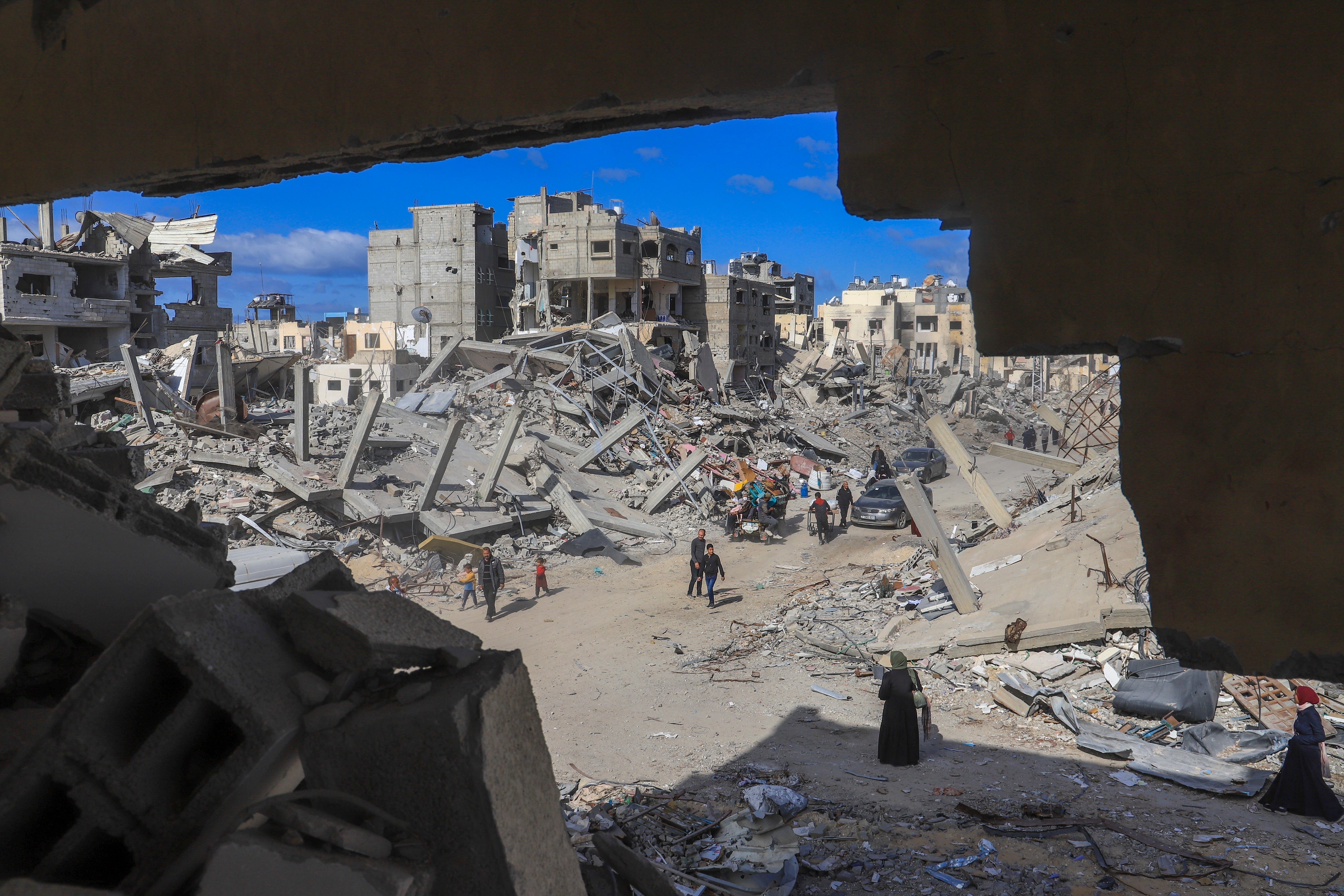 Palestinians walk through the rubble caused by the Israeli air and ground offensive in Rafah in the southern Gaza Strip