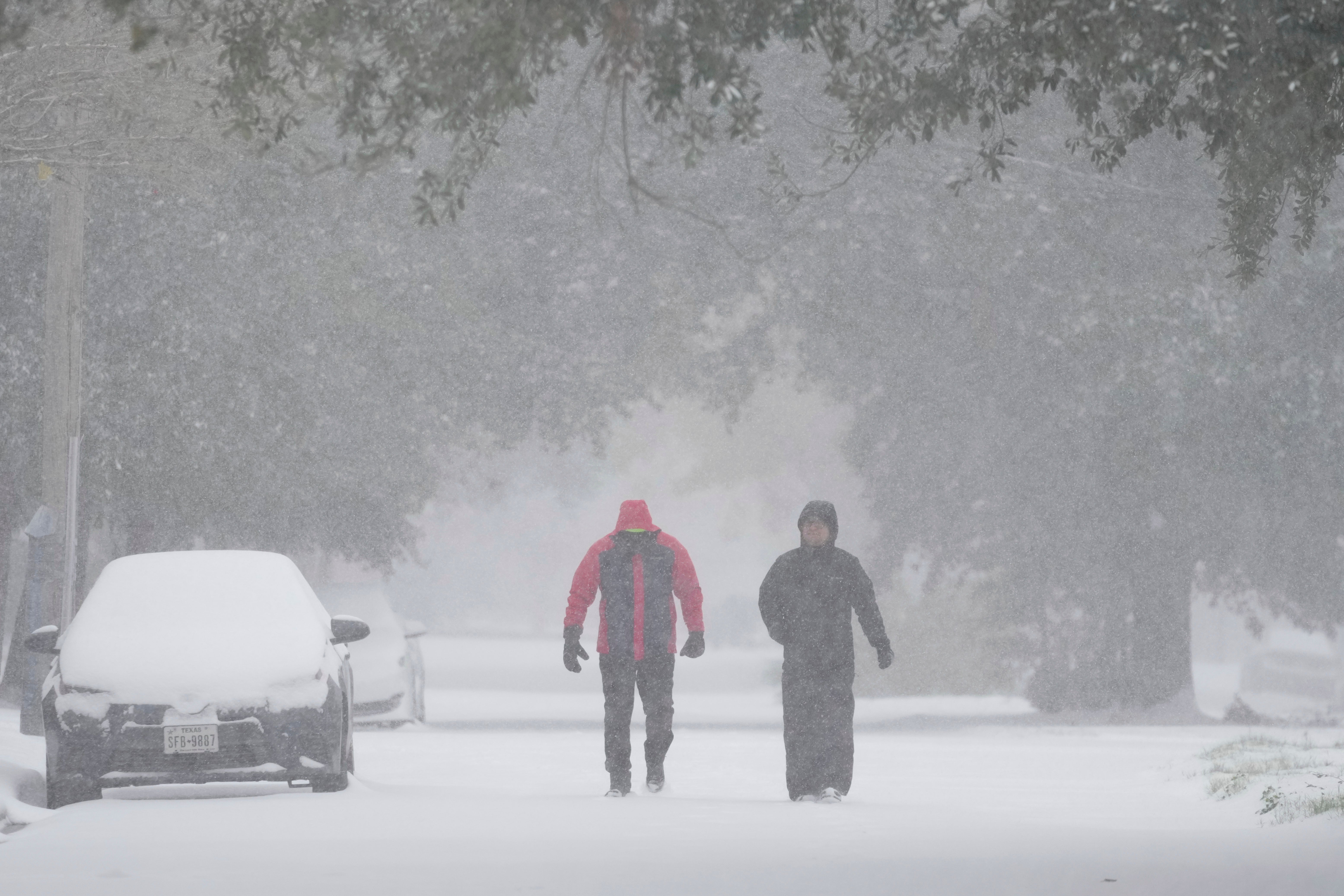 People take a walk in a Houston, Texas, neighborhood on Tuesday. Winter weather brought multiple travel hazards to the region