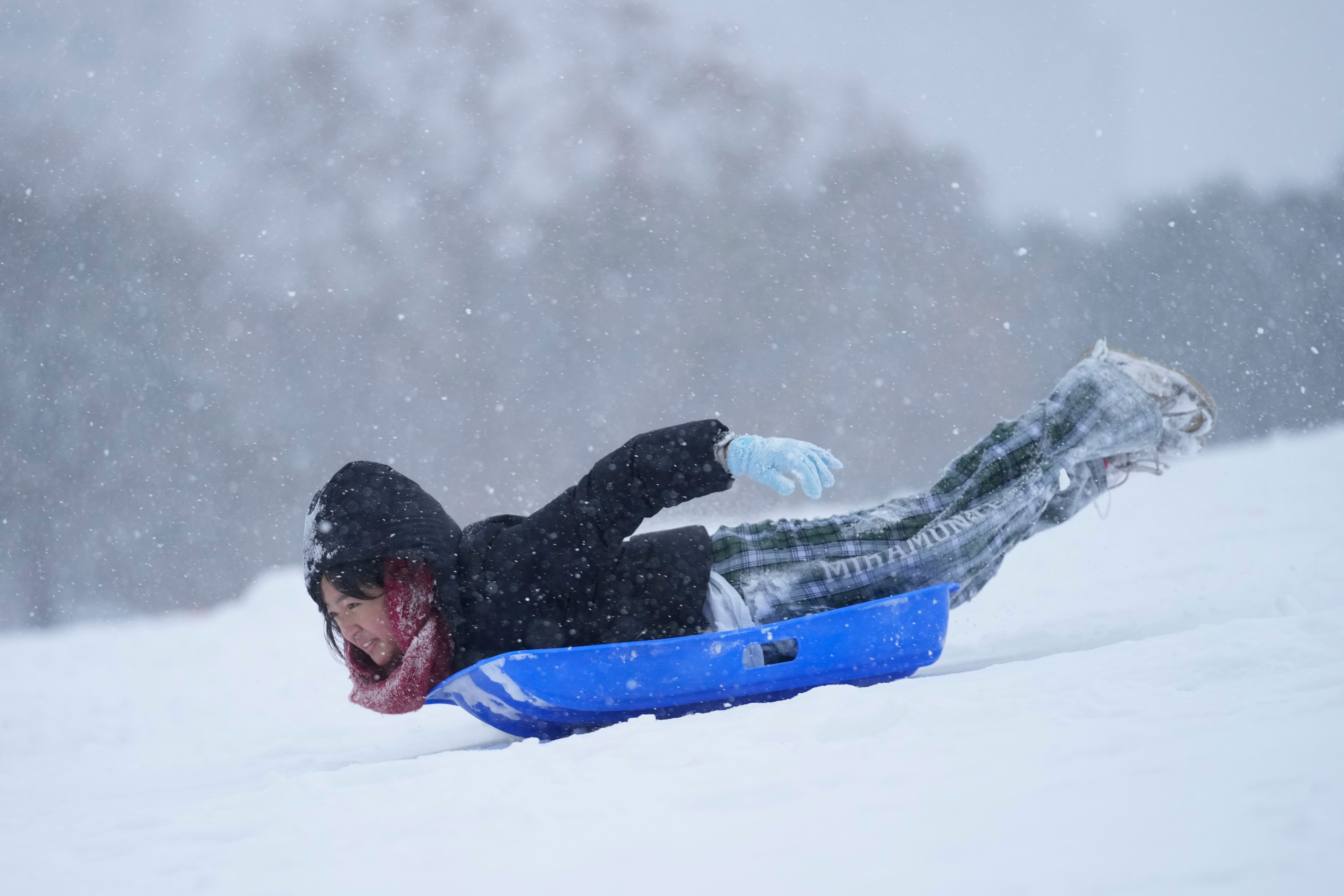 A person sleds down a hill on Tuesday at Herman Park in Houston, Texas. The city warned the snow was potentially dangerous for residents