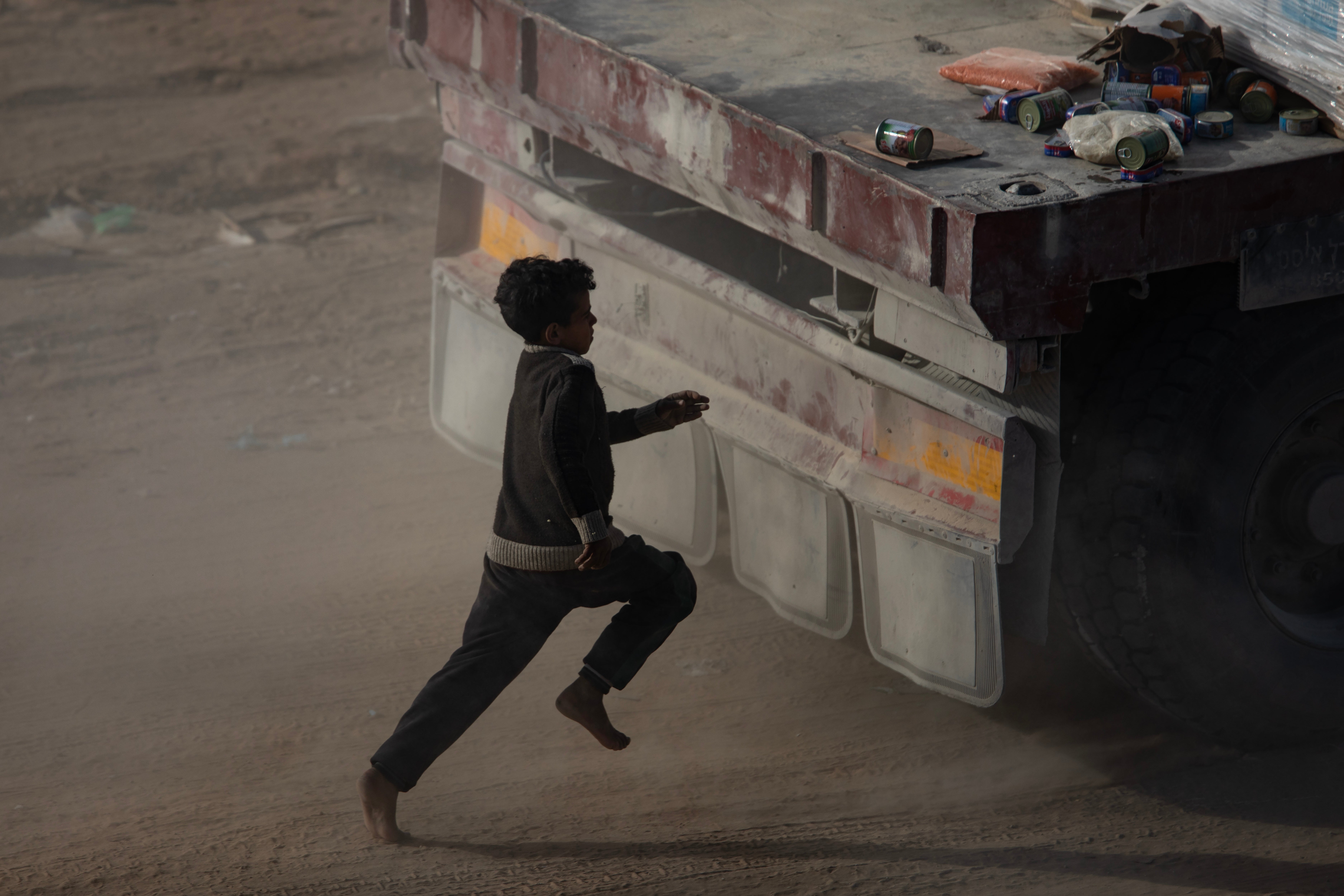 A displaced Palestinian chases a humanitarian aid truck amid a ceasefire between Israel and Hamas in Rafah