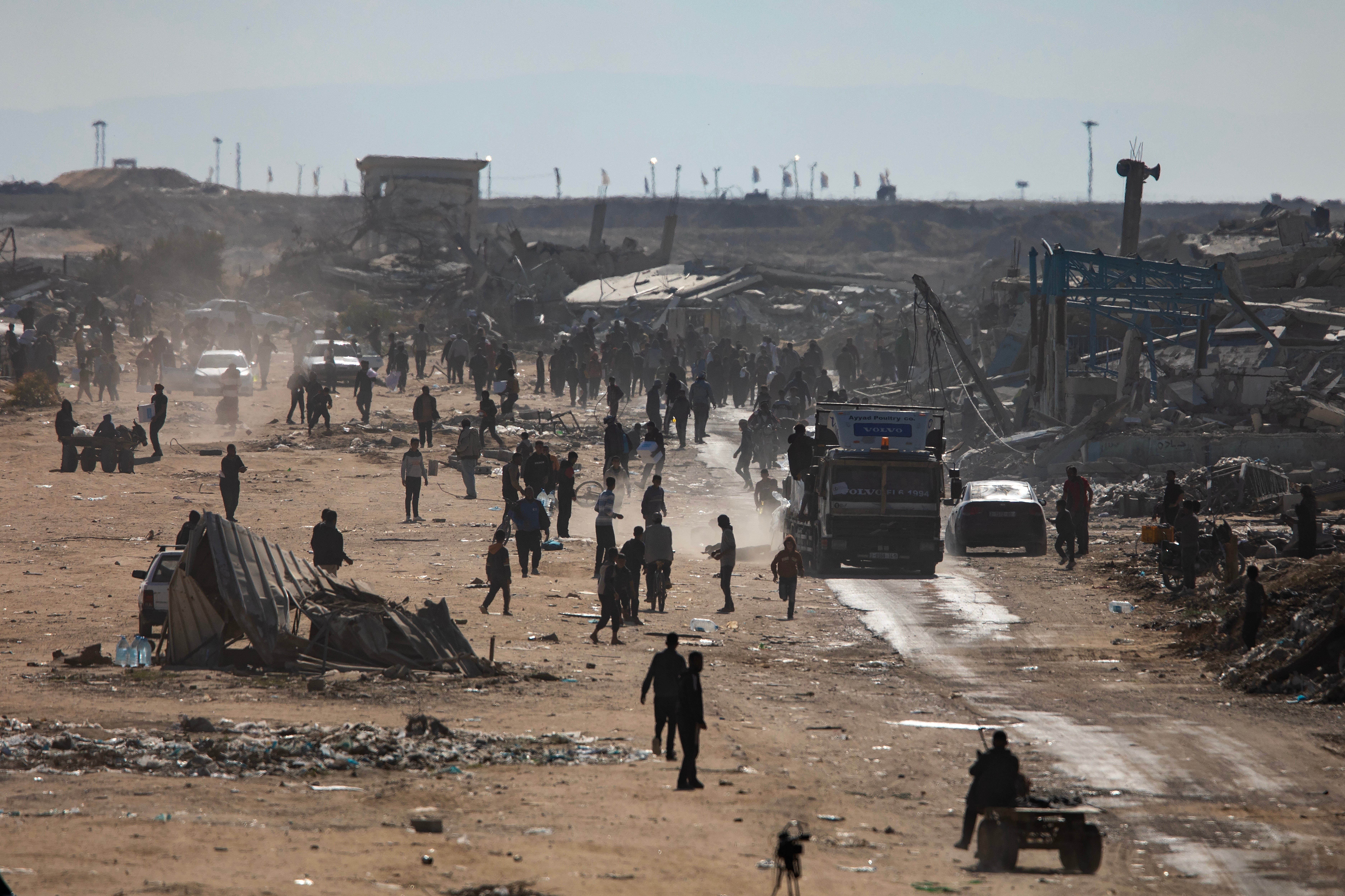 Displaced Palestinians chase a humanitarian aid truck amid a ceasefire between Israel and Hamas in Rafah