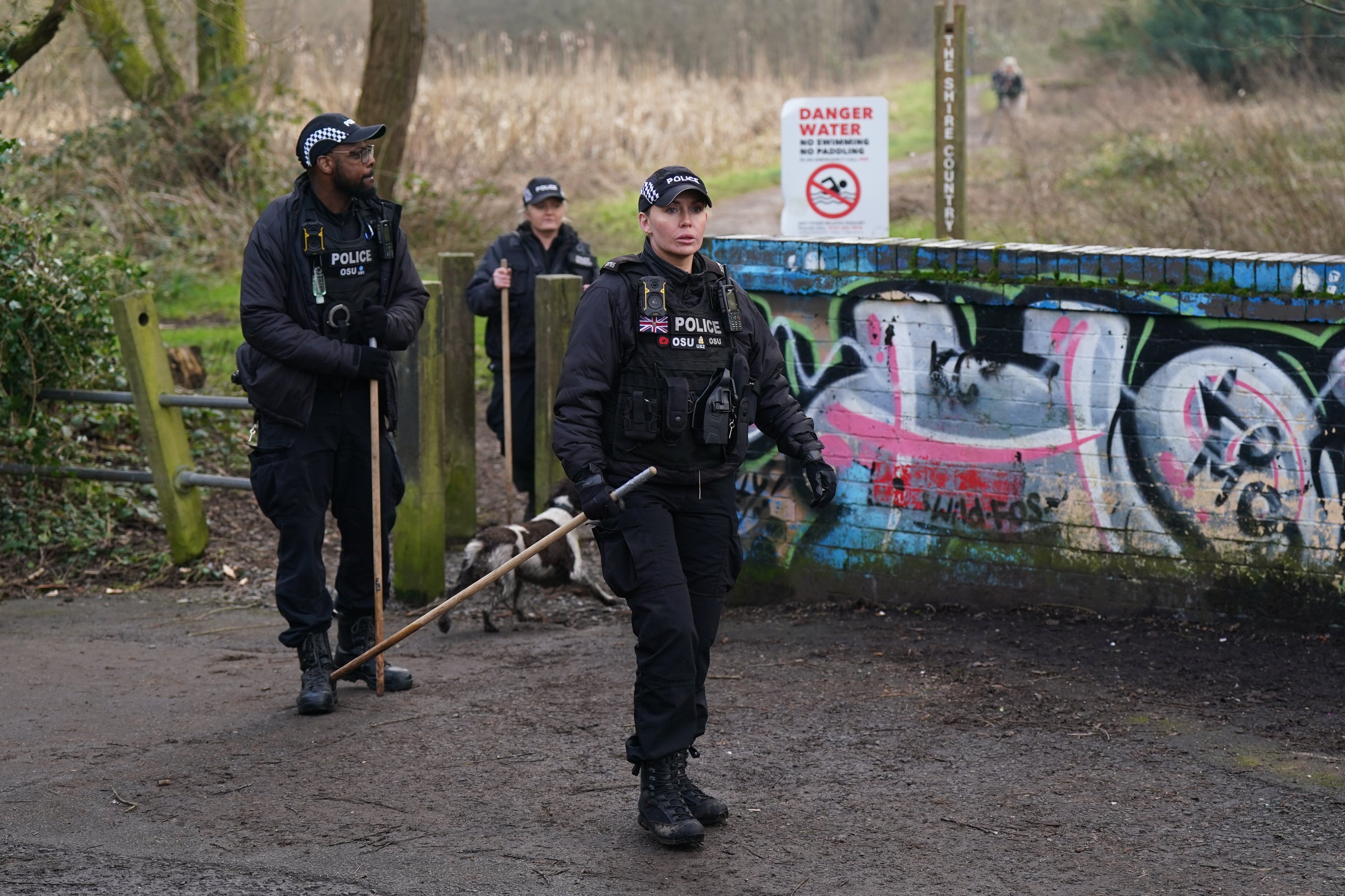 Officers sweep the woodland for clues