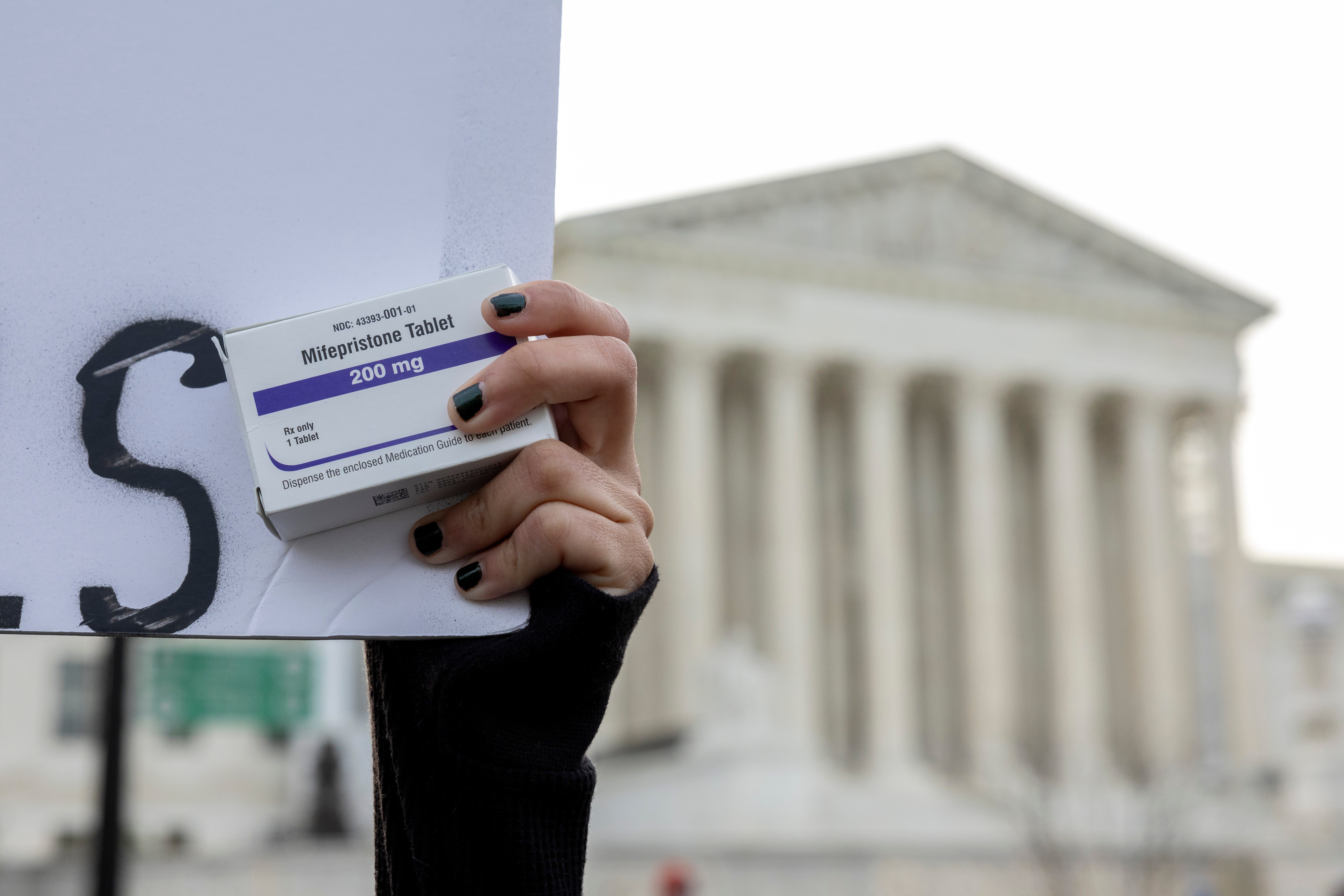 An abortion-rights activist holds a box of mifepristone pills as demonstrators rally outside Supreme Court. A federal judge in Texas allowed for a 2022 case concerning the approval of the abortion drug less than a week before the 52nd anniversary of Roe v. Wade