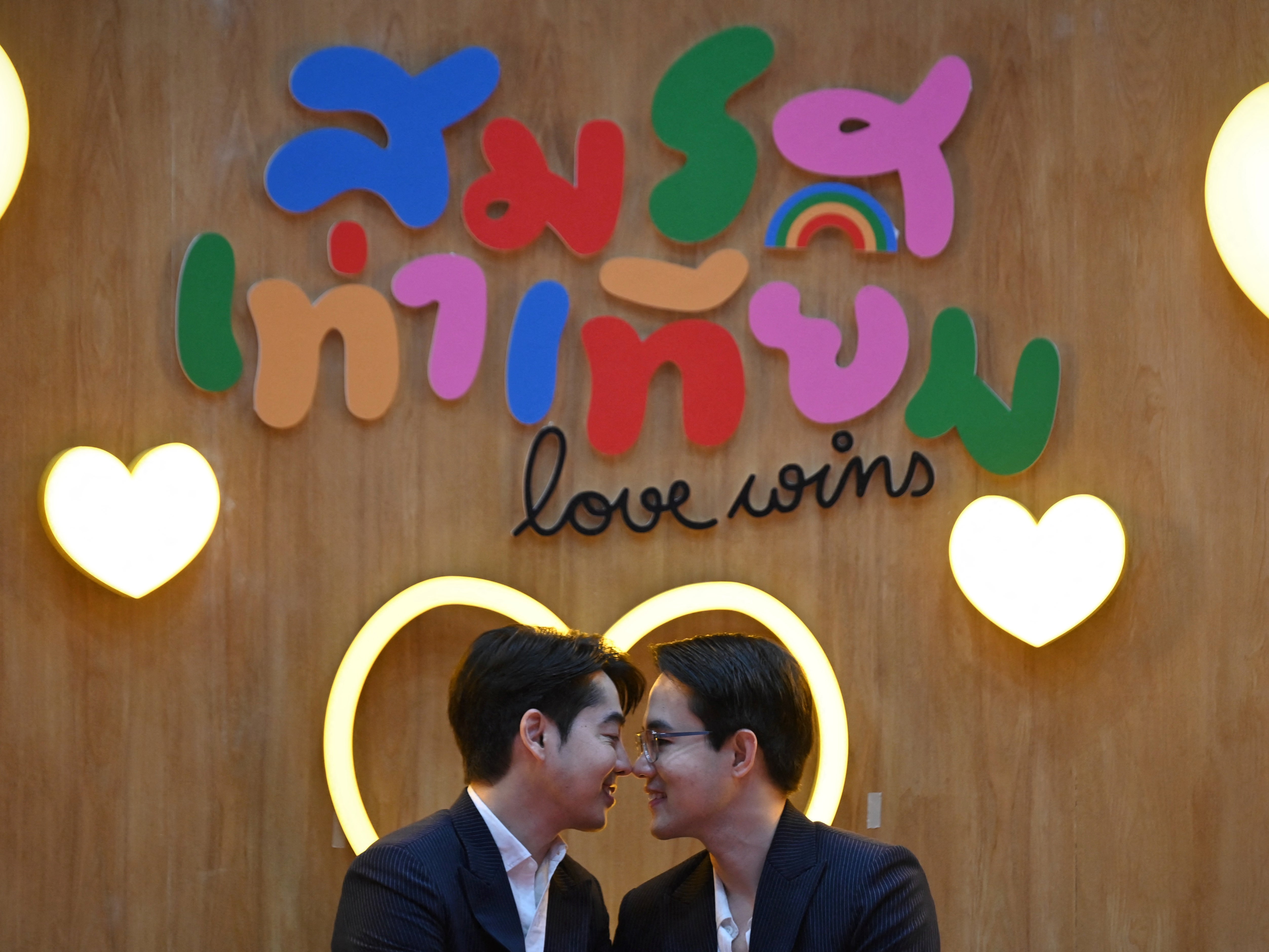 <p>A couple poses for pictures at a marriage registration event at Paragon shopping mall in Bangkok on 23 January 2025. A high-profile gay couple married in Thailand on 23 January as the kingdom’s same-sex marriage law went into effect, an AFP journalist saw, among the first of hundreds expected to do so</p>