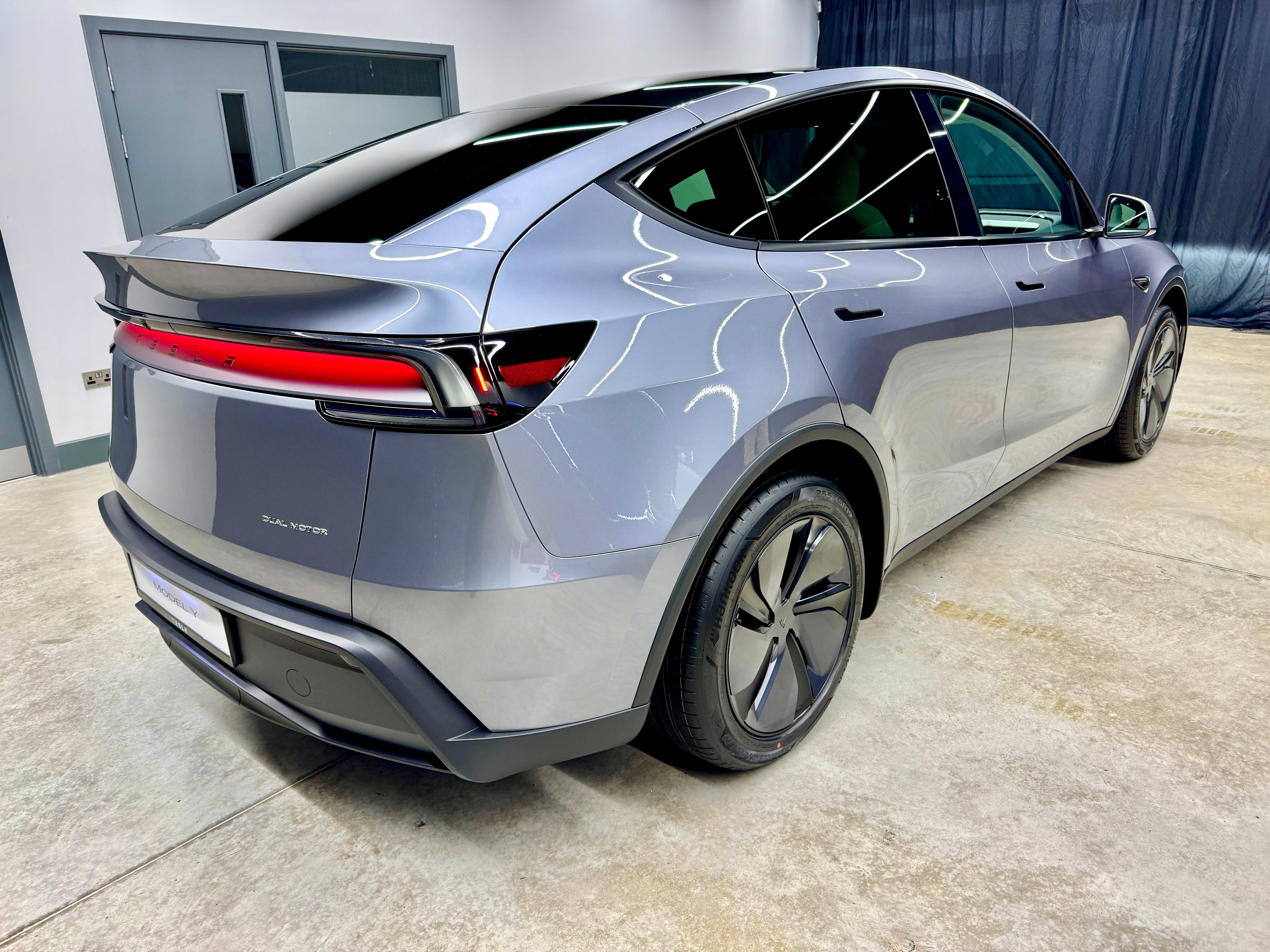 The rear of the all-new Tesla Model Y features clever reflective lighting in a full-width lighting strip.