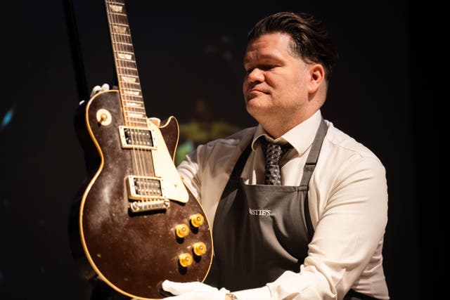 An art handler holds a 1954 Gibson Les Paul known as The Oxblood (James Manning/PA)