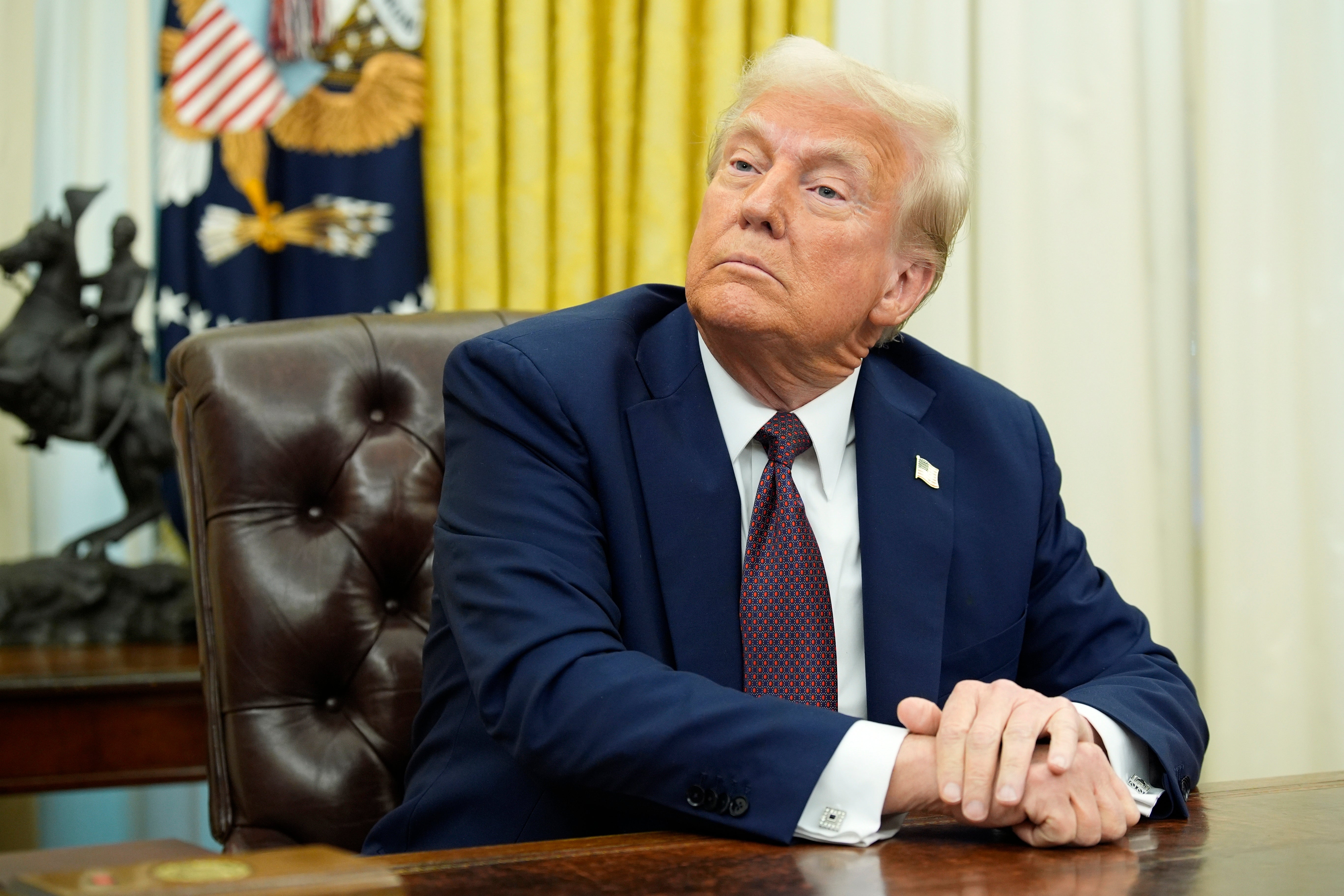 President Donald Trump sits in the Oval Office after signing executive orders. Young lawyers were informed that their offers for the Attorney General’s Honors Program was revoked due to a federal hiring freeze, according to a report