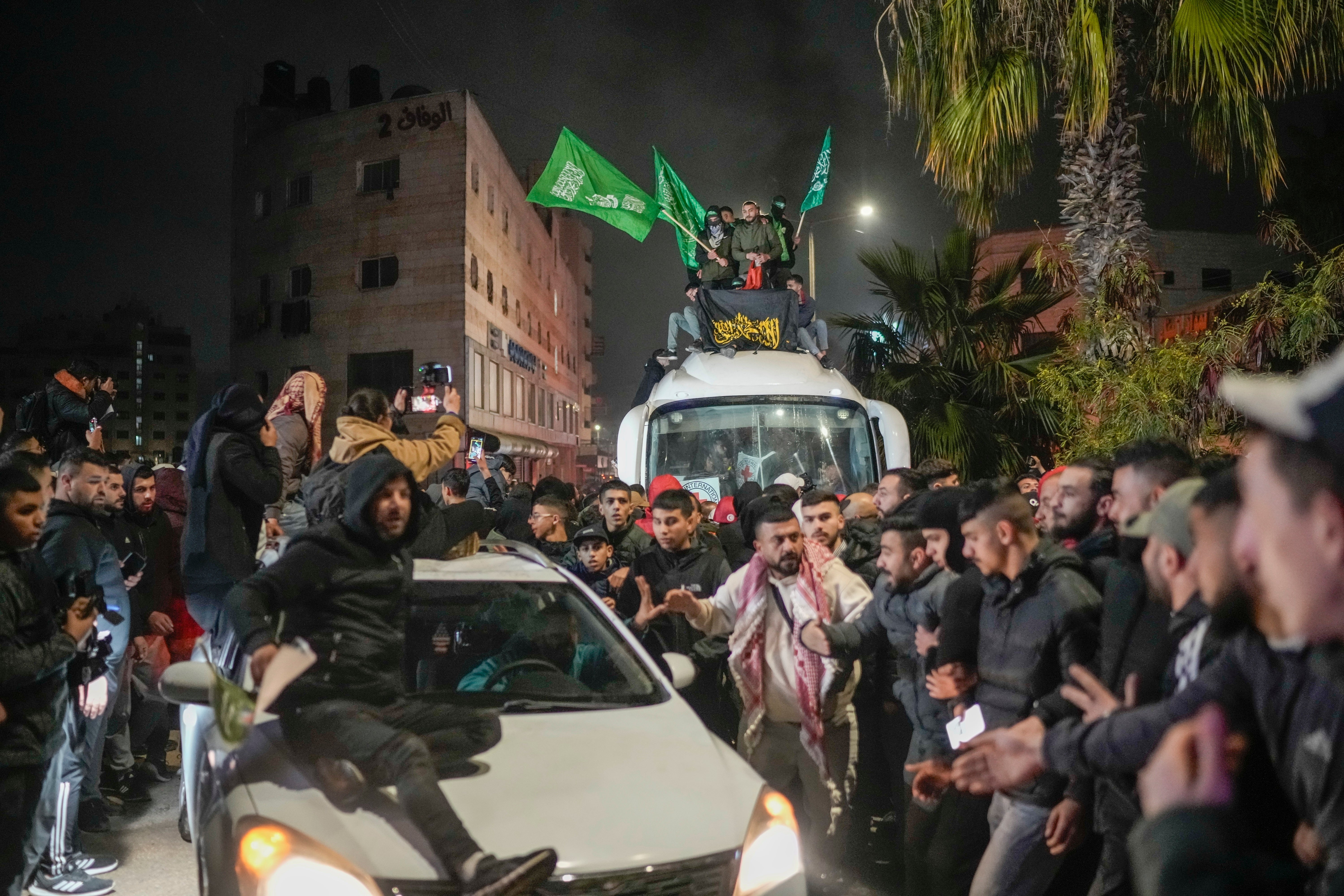 A crowd gathers around a bus carrying Palestinian prisoners who were released from an Israeli prison as part of the ceasefire deal