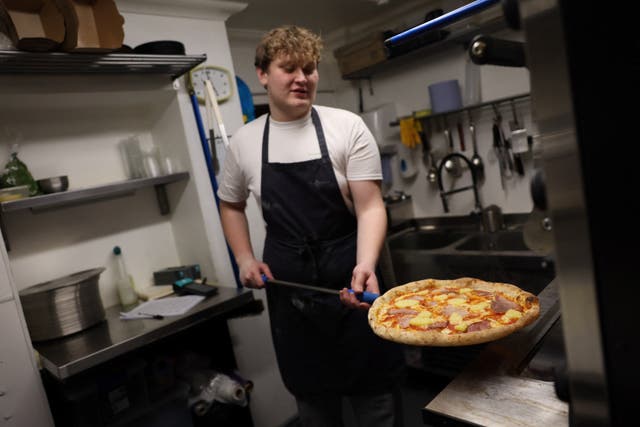 <p>Chef Oliver Bardwell prepares a Hawaiian, ham, and pineapple-topped pizza at Lupa Pizza restaurant in Norwich</p>