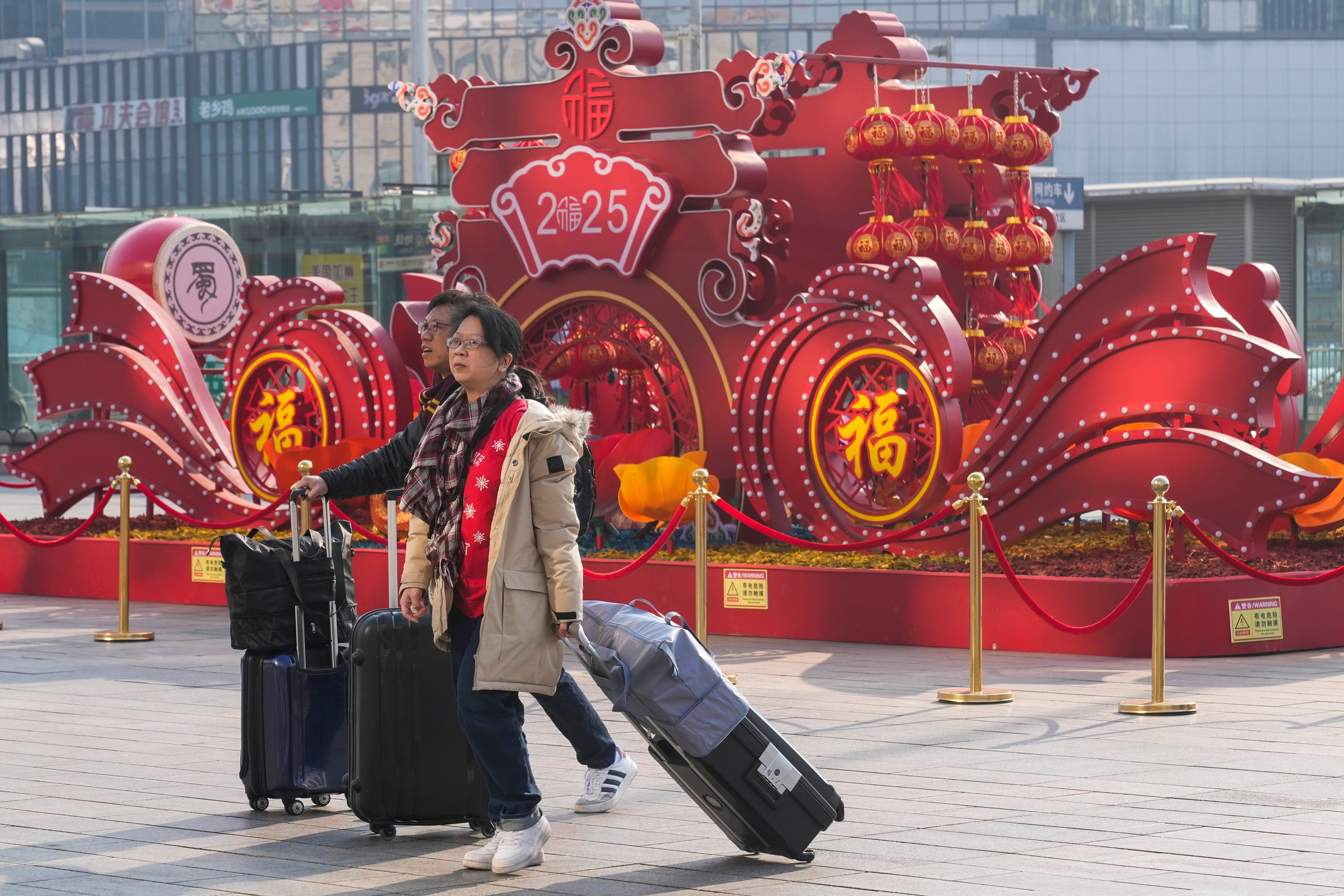 Travelers walk towards the departure hall to catch their trains at the Beijing West Railway Station ahead of the Lunar New Year in Beijing on Friday, Jan. 24, 2025