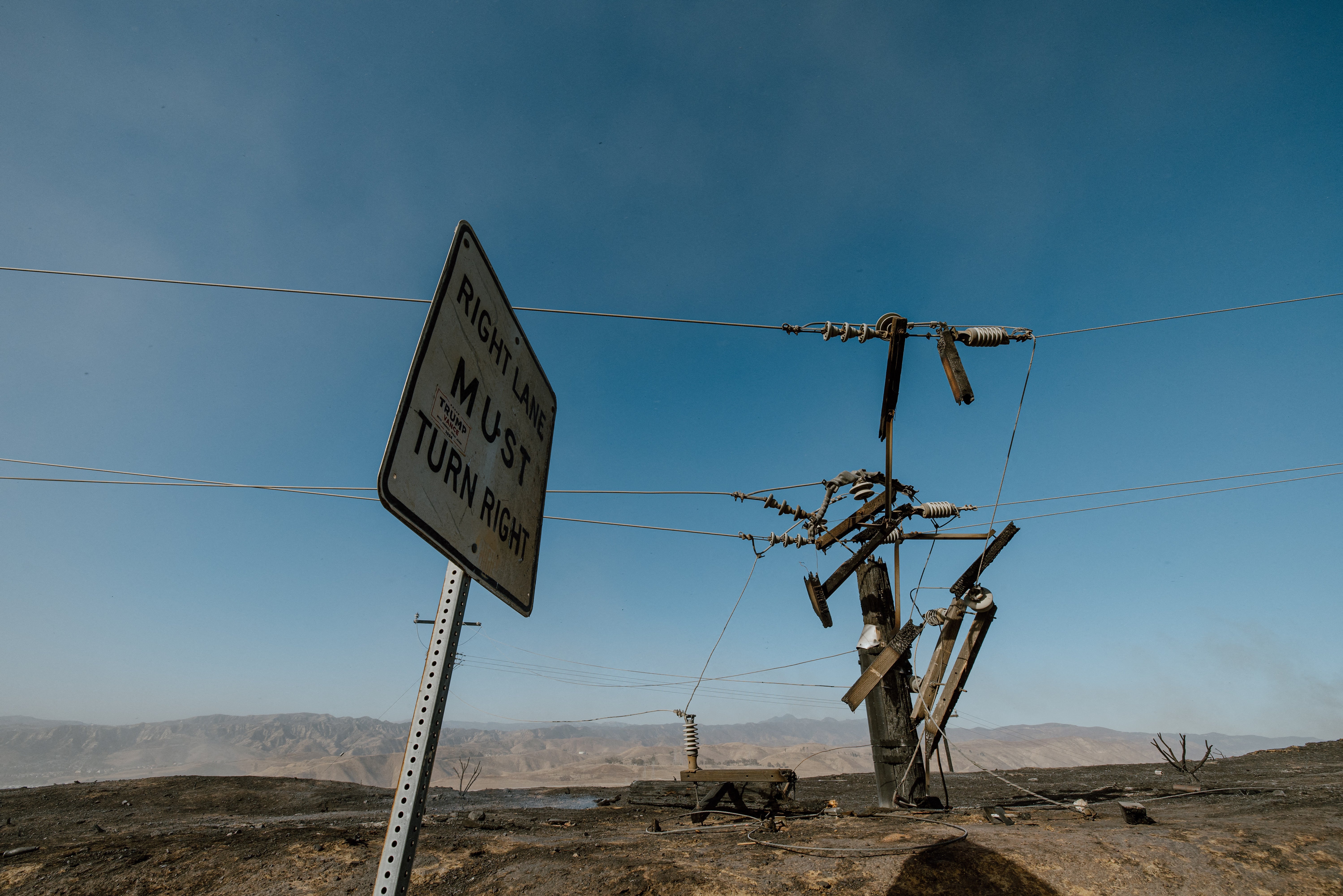 A charred road sign and damaged utility pole stand amid a scorched landscape left by the Hughes fire near Santa Clarita, California, on Thursday. The fire is now more than half contained