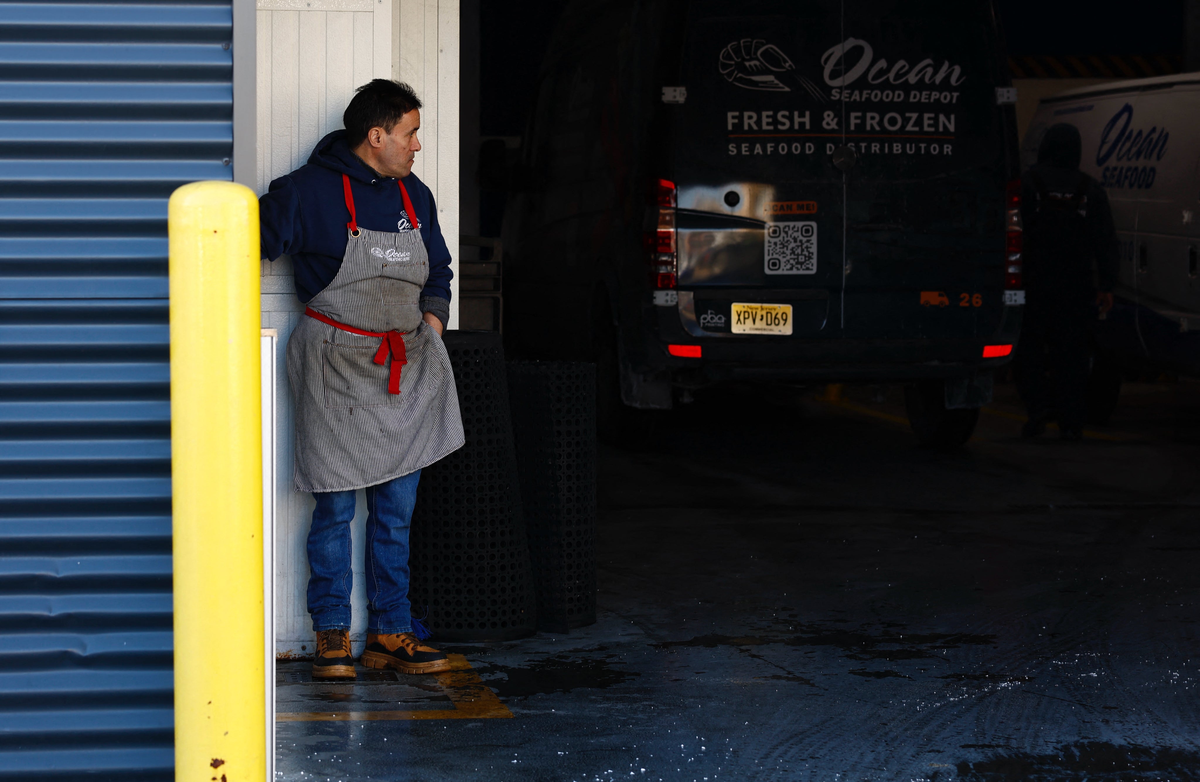 A worker stands at the parking area of the Ocean Seafood Depot where several workers were arrested by Immigration and Customs Enforcement officers