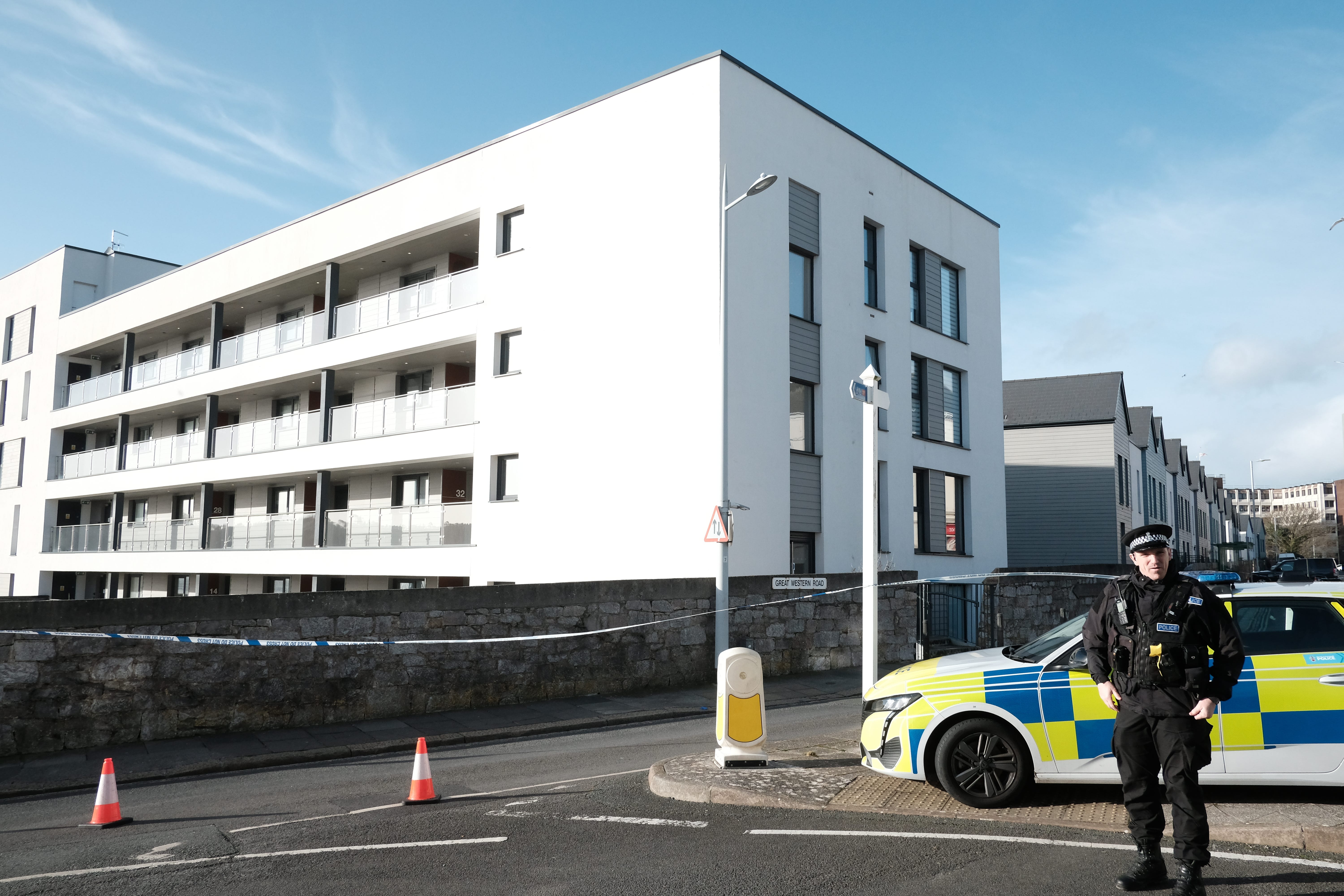 A police officer stands outside a block of flats in Plymouth