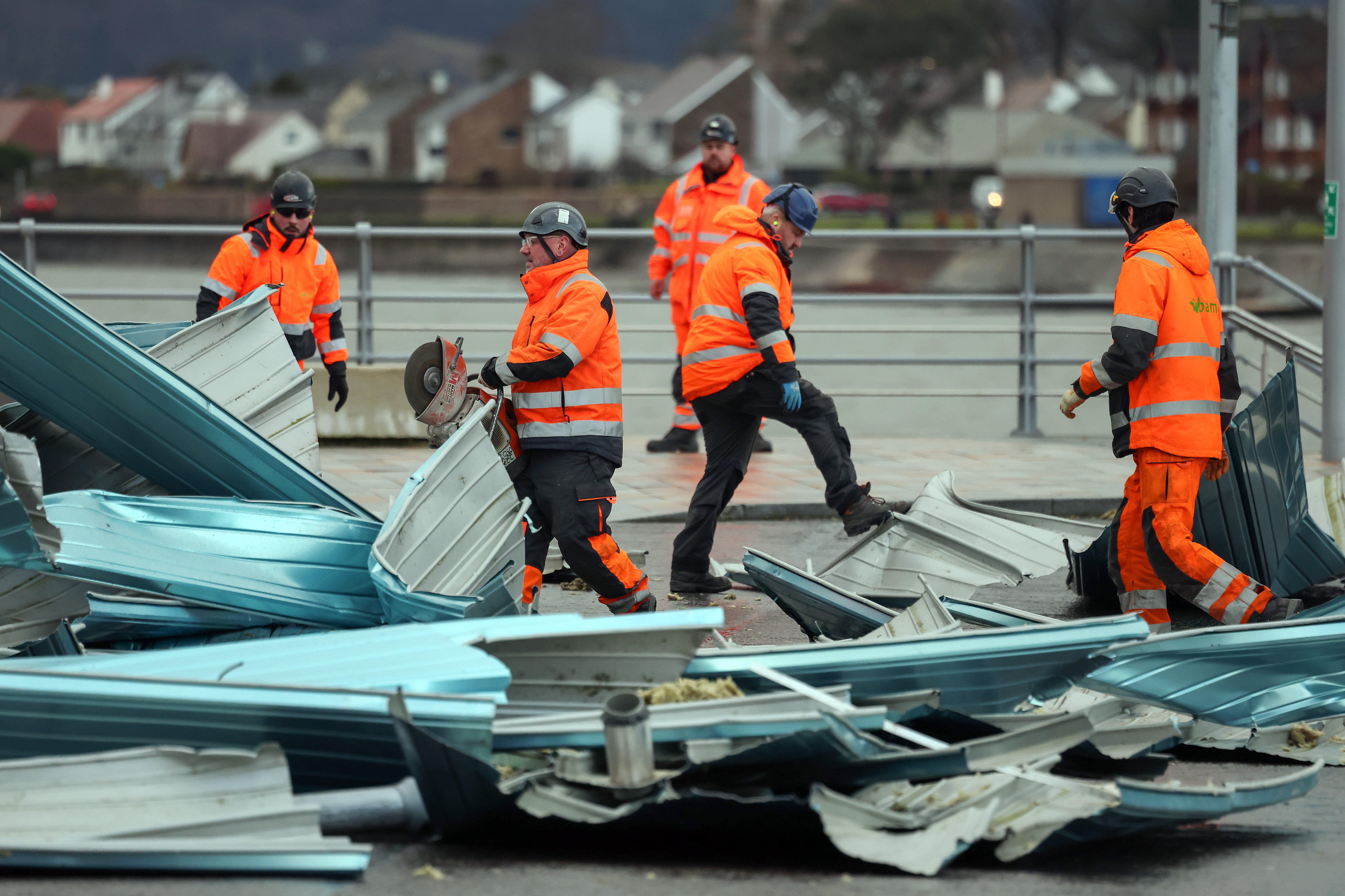 Workers clear debris from the roof blown off a leisure centre during storm Eowyn