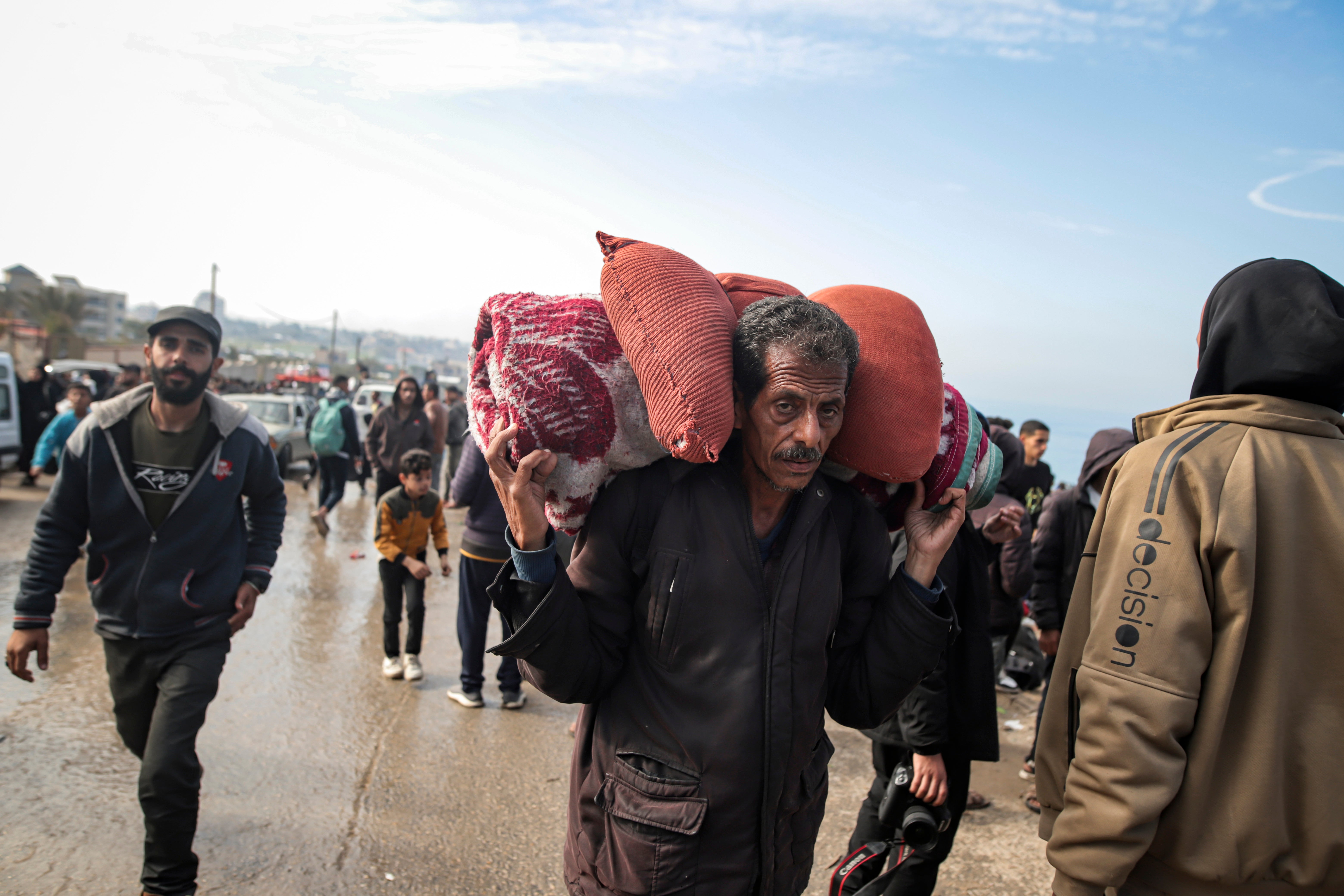 Displaced Palestinians gather with their belongings near a roadblock on the al Rashid Street