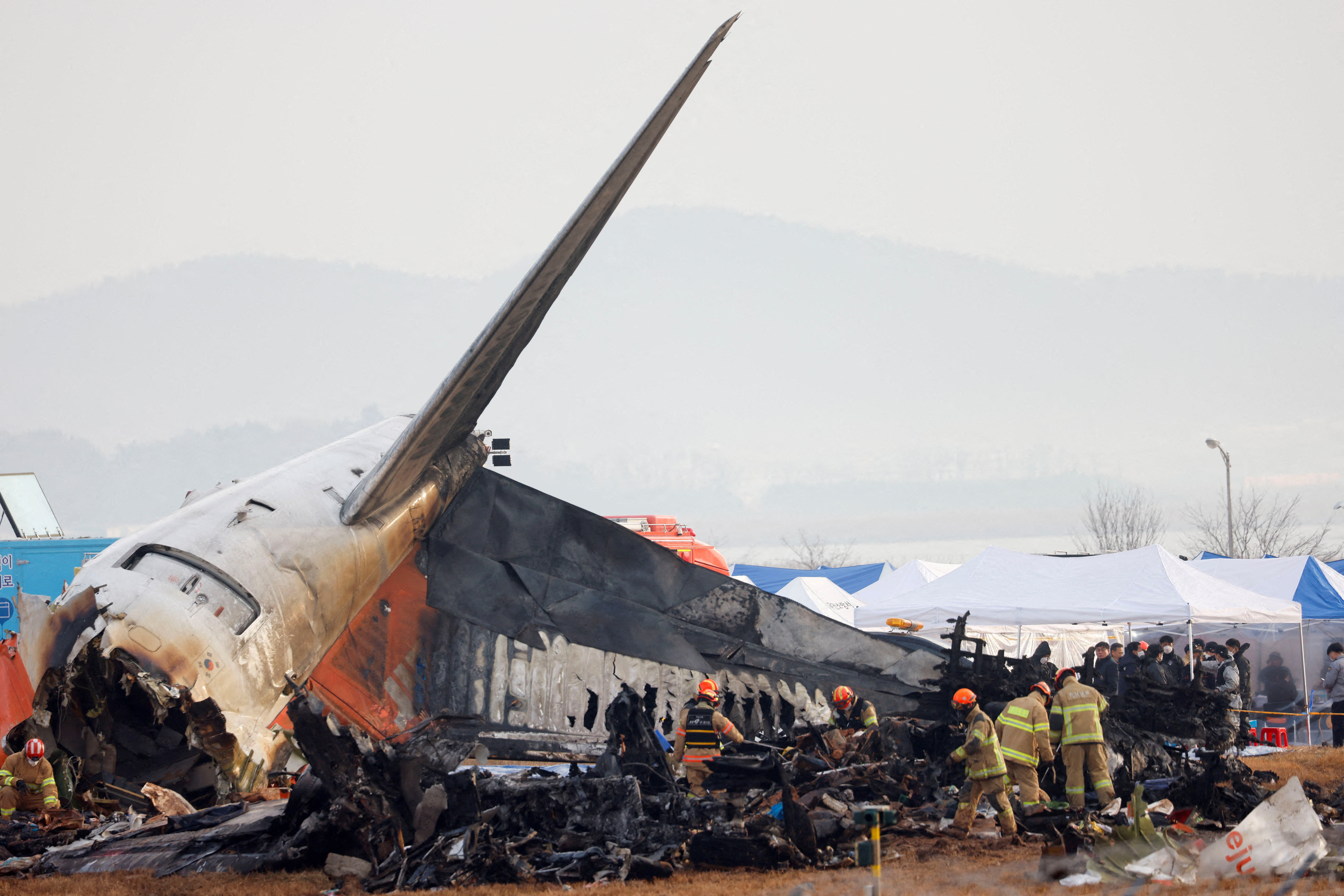 <p>People work at the site where an aircraft went off the runway and crashed at the Muan airport in South Korea </p>