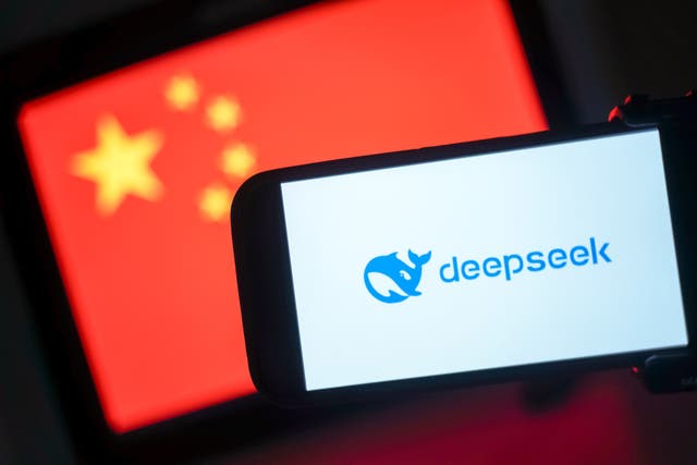 <p>The DeepSeek logo is seen on a phone in front of a flag of China </p>