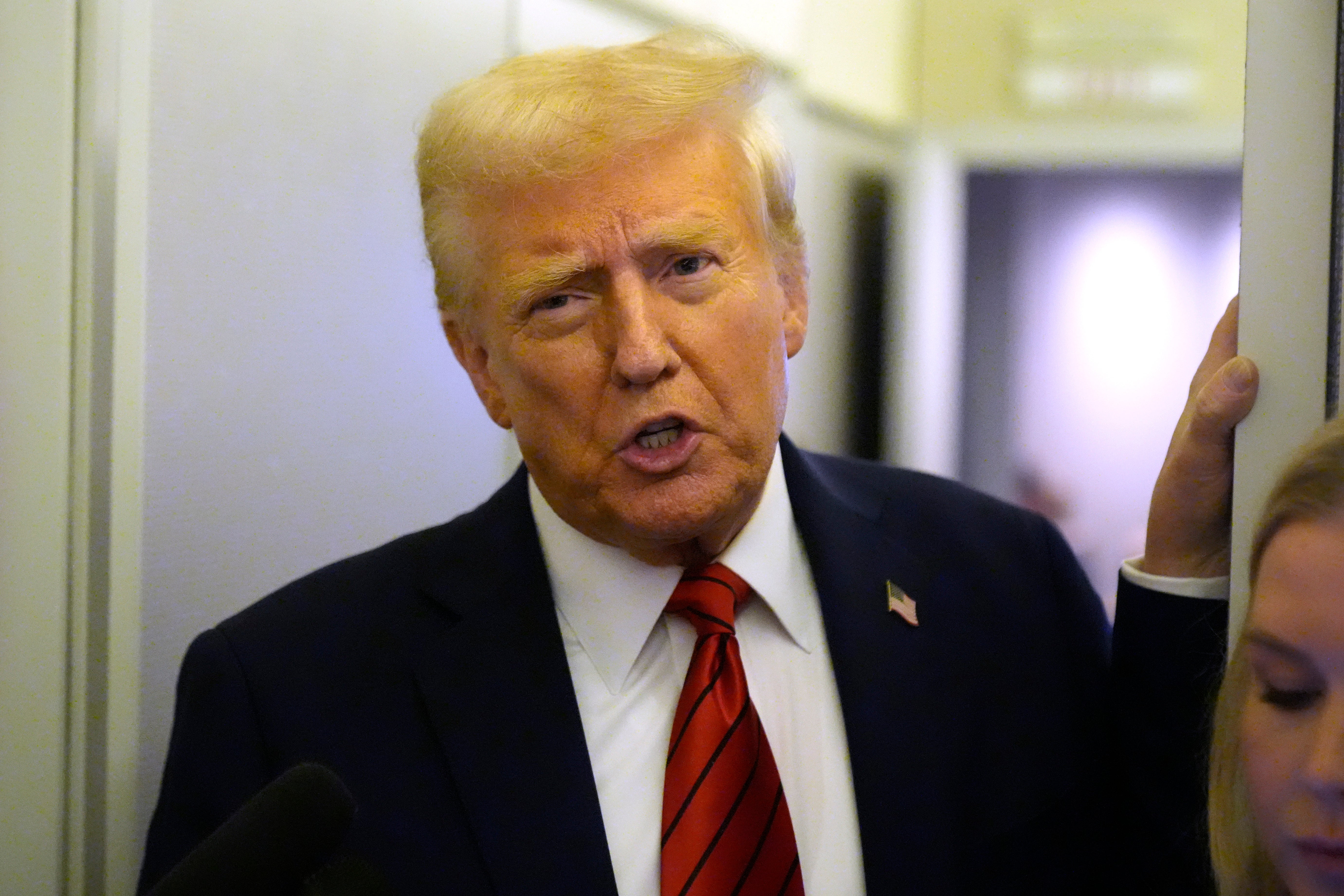 President Donald Trump speaks to reporters aboard Air Force One. His administration has issued a freeze on all government loans and grants