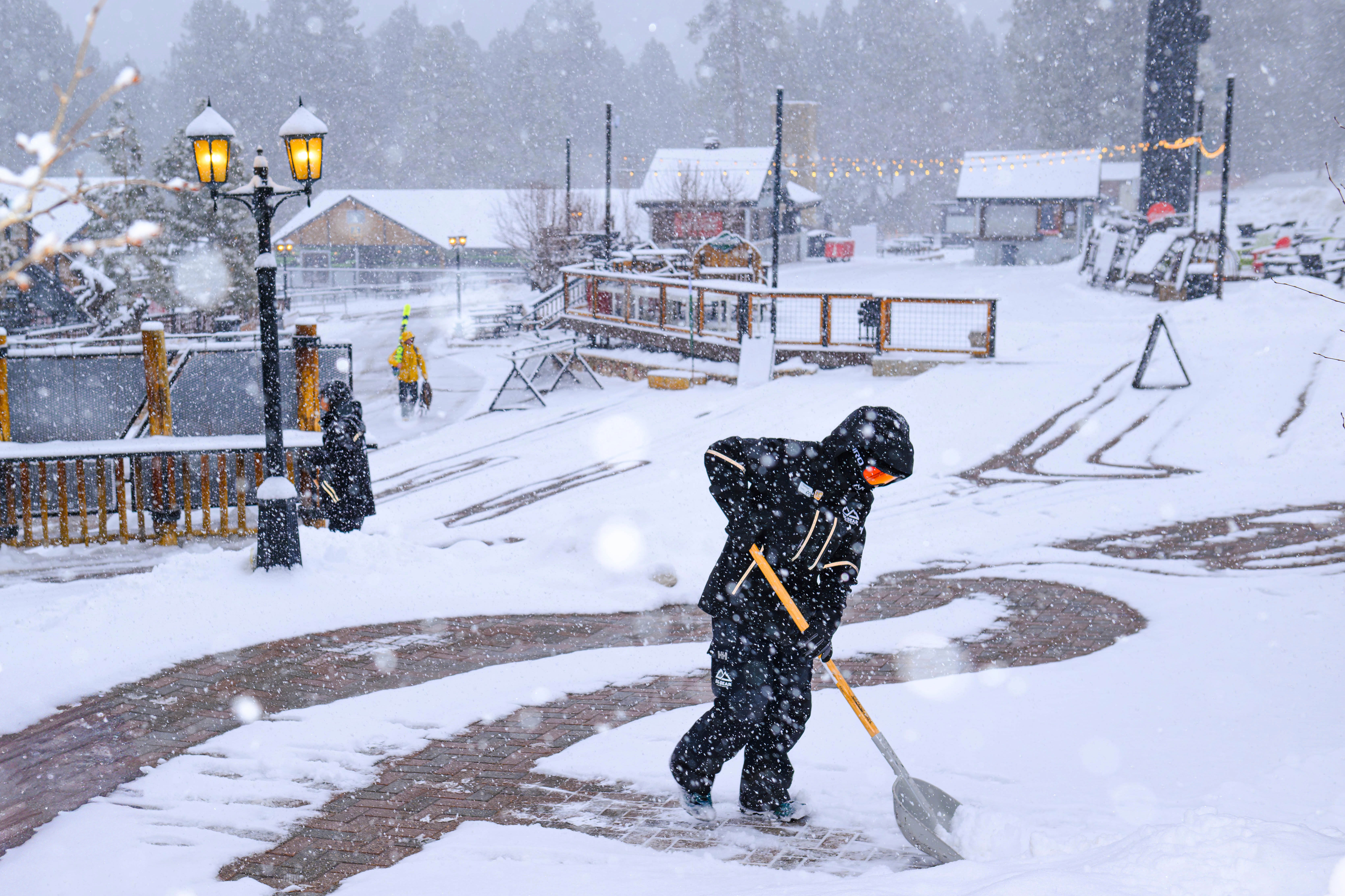 A worker clears snow at the Big Bear Mountain Resort in Big Bear Lake, California, on Monday. The system, which is heading eastward after providing wildfire-ravaged Southern California with some much-needed precipitation, is bringing winter weather and rain across the Southwest