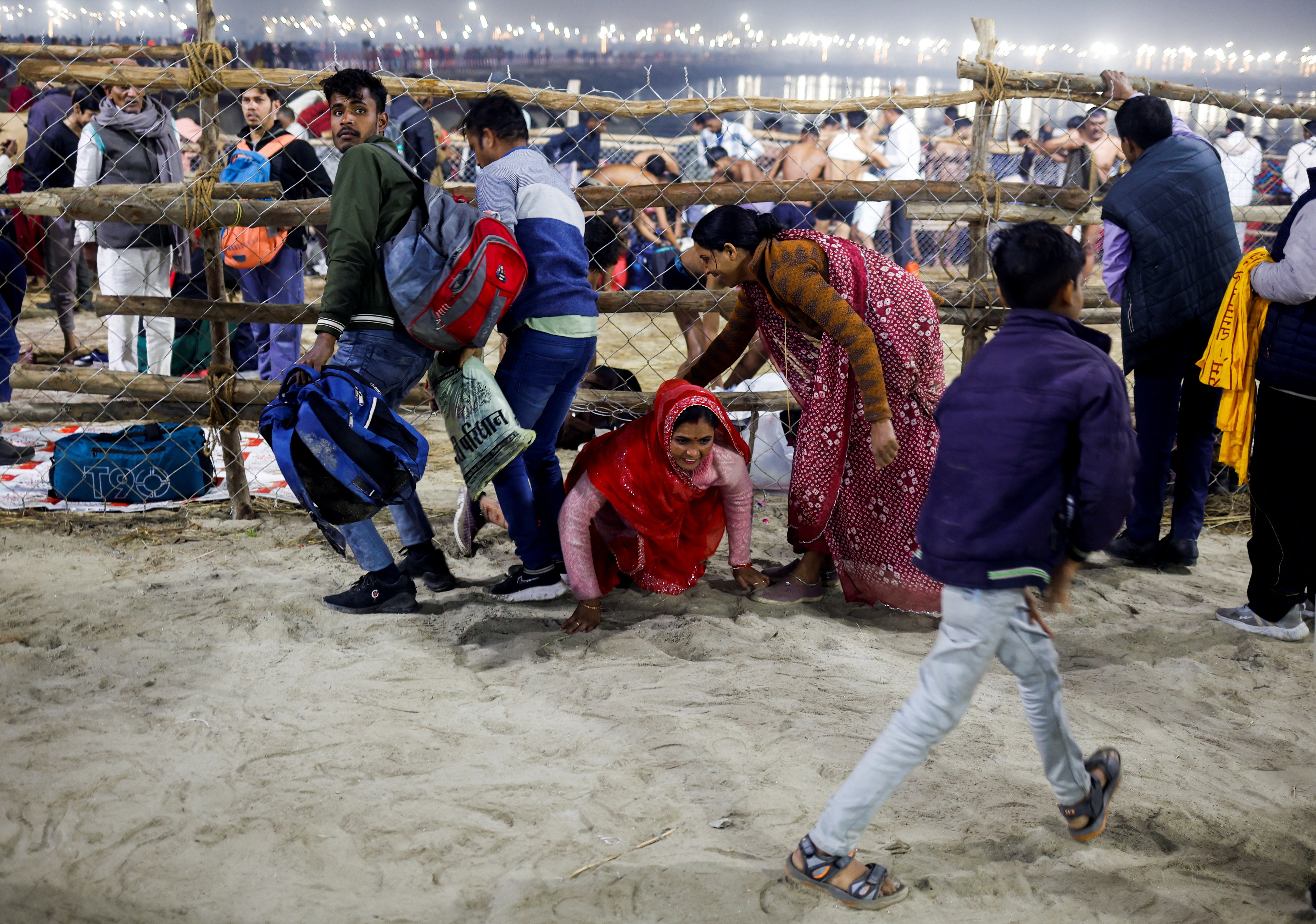 A woman crawls under a fence, after a deadly stampede before the second ‘shahi snan’