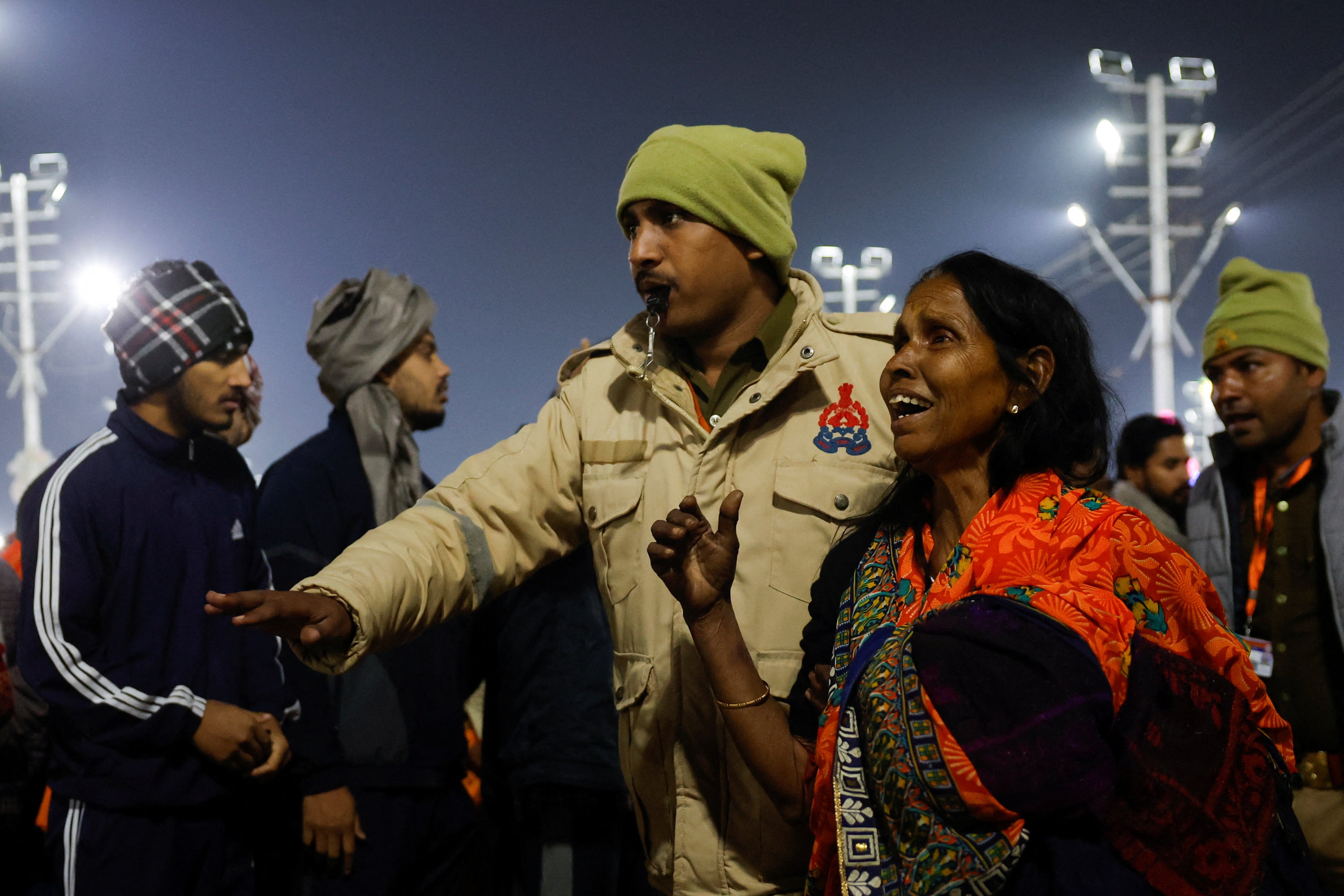 A policeman escorts a devotee aft  a stampede occurred earlier  the 2nd  royal bath astatine  the Maha Kumbh Mela