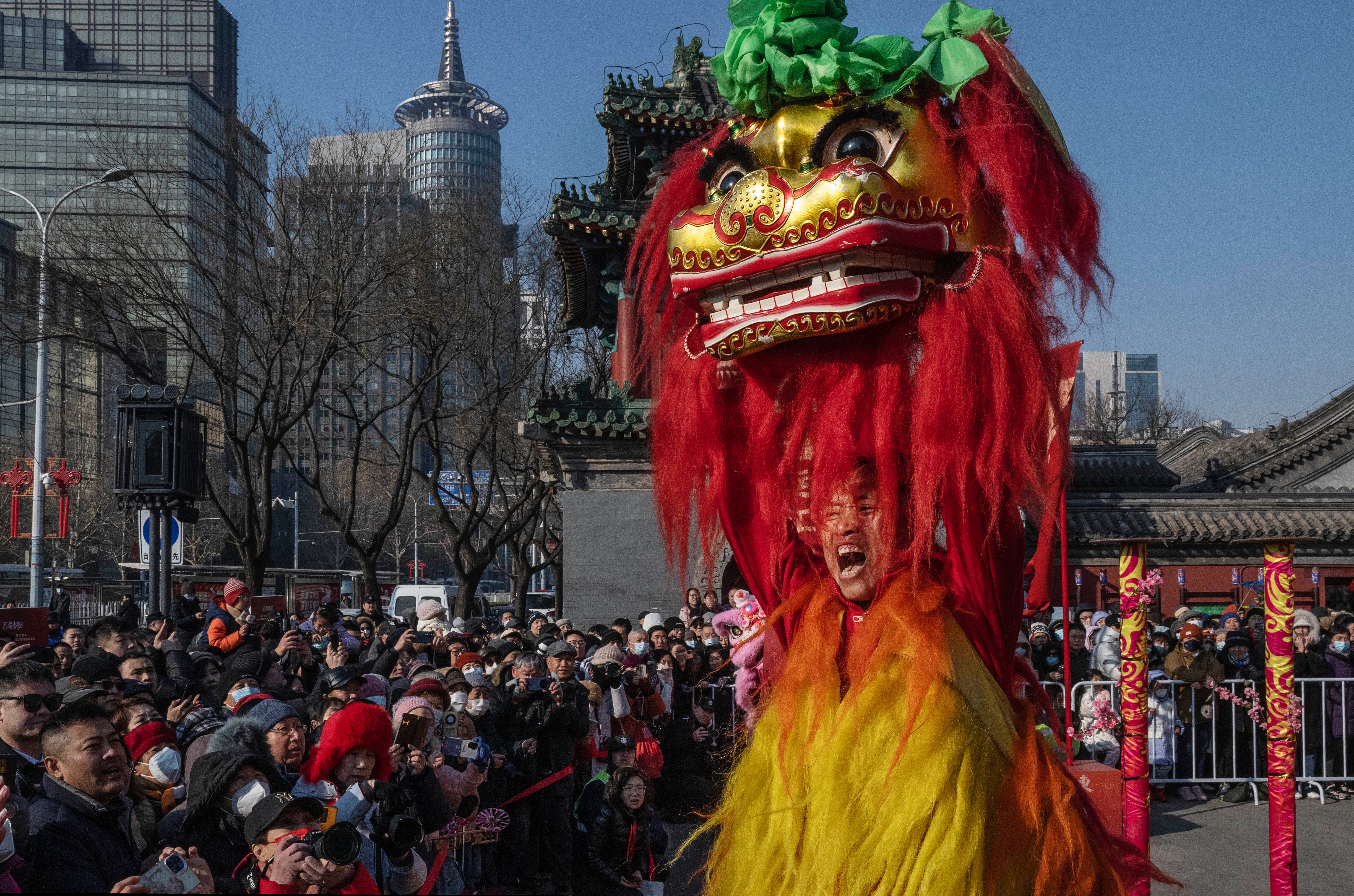 A lion dancer shouts as people watch a traditional lion dance for good luck and fortune