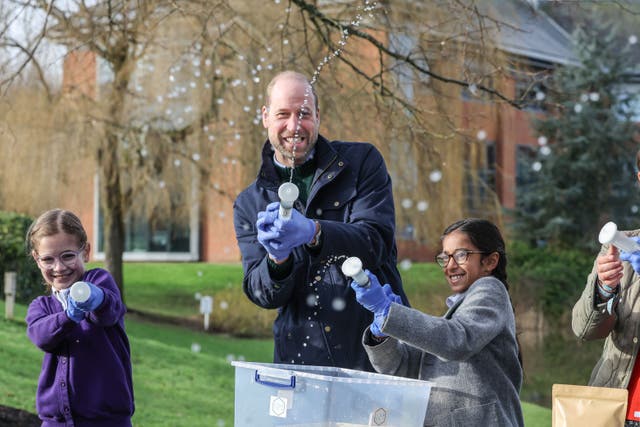 The Prince of Wales with local school children as they filter DNA samples through a syringe after extracting water from a local pond (Richard Pohle/The Times/PA)
