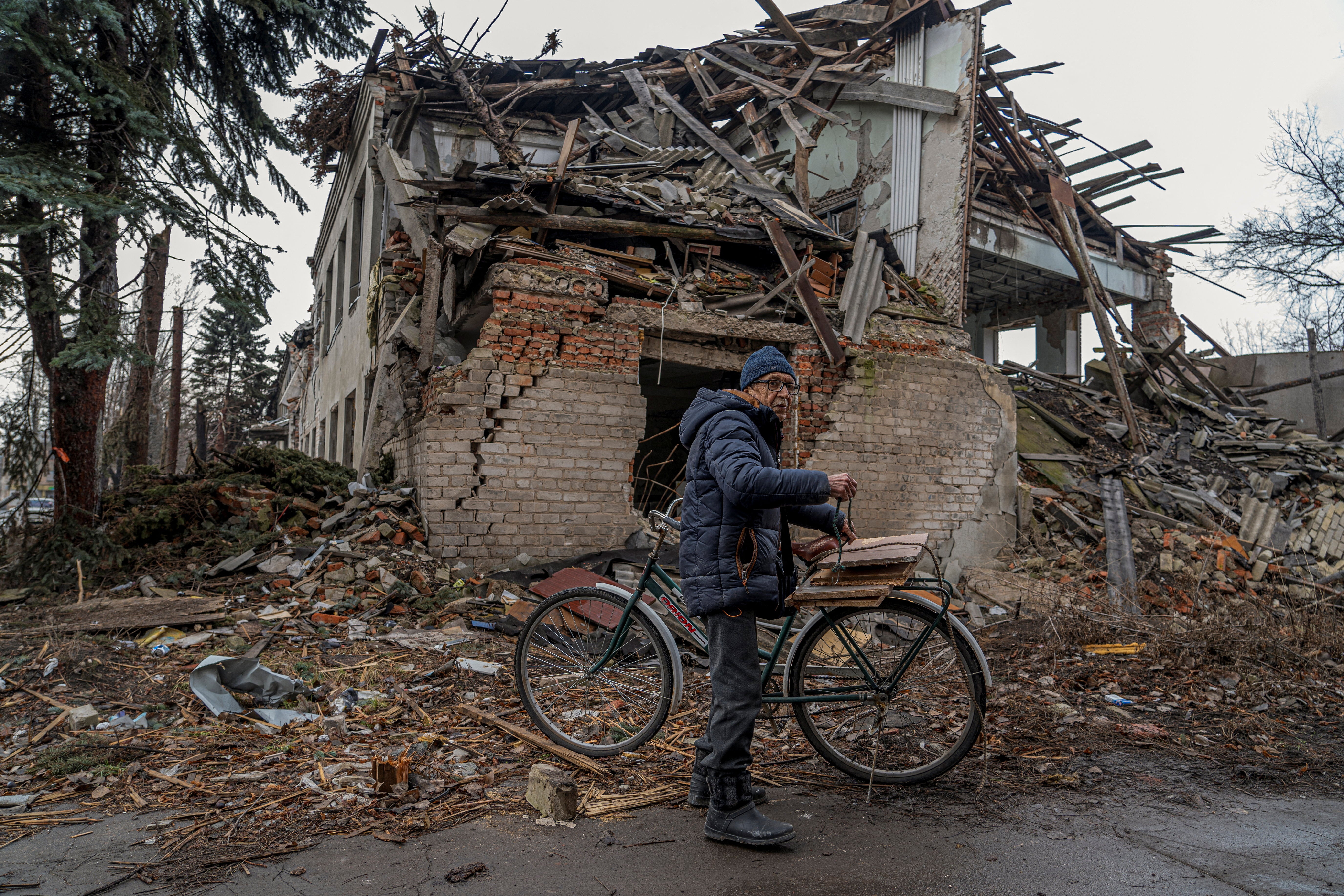 Mykola, 76, attaches firewood to his bicycle in front of a building damaged by Russian military strikes, amid Russia's attack on Ukraine, in Pokrovsk, Donetsk region, Ukraine January 25, 2025