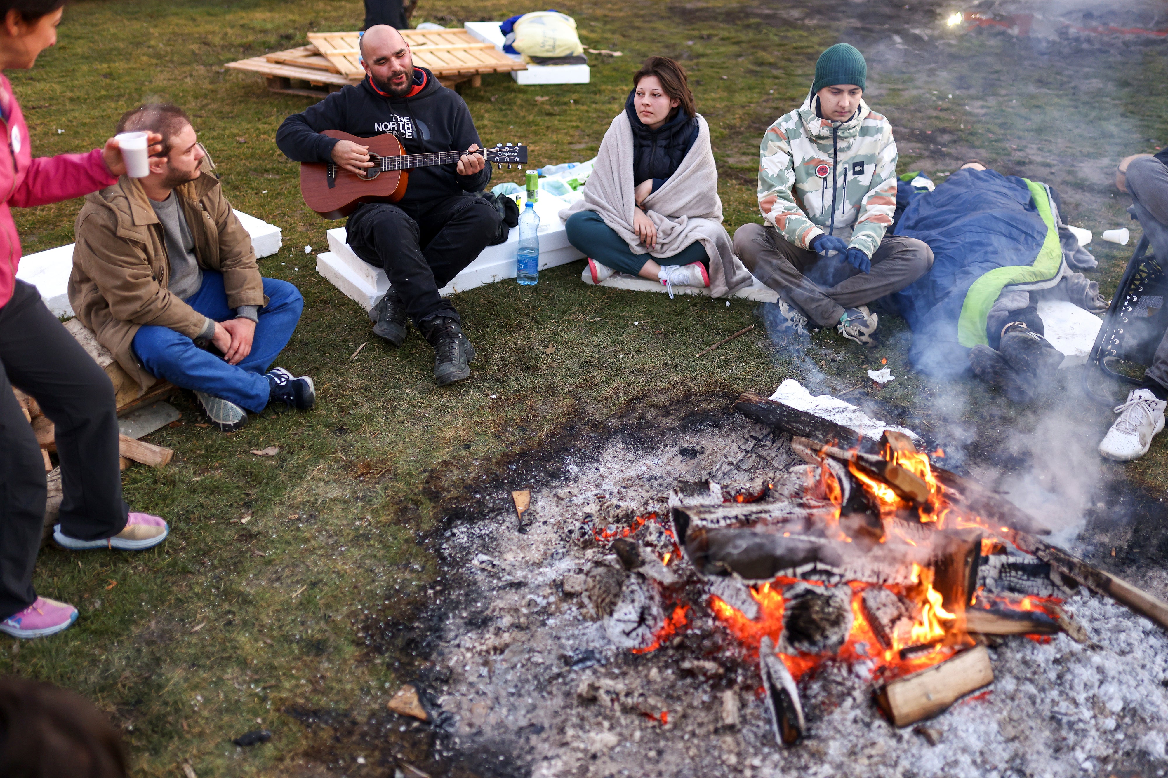 Students sit around a fire as they try to warm up during a protest