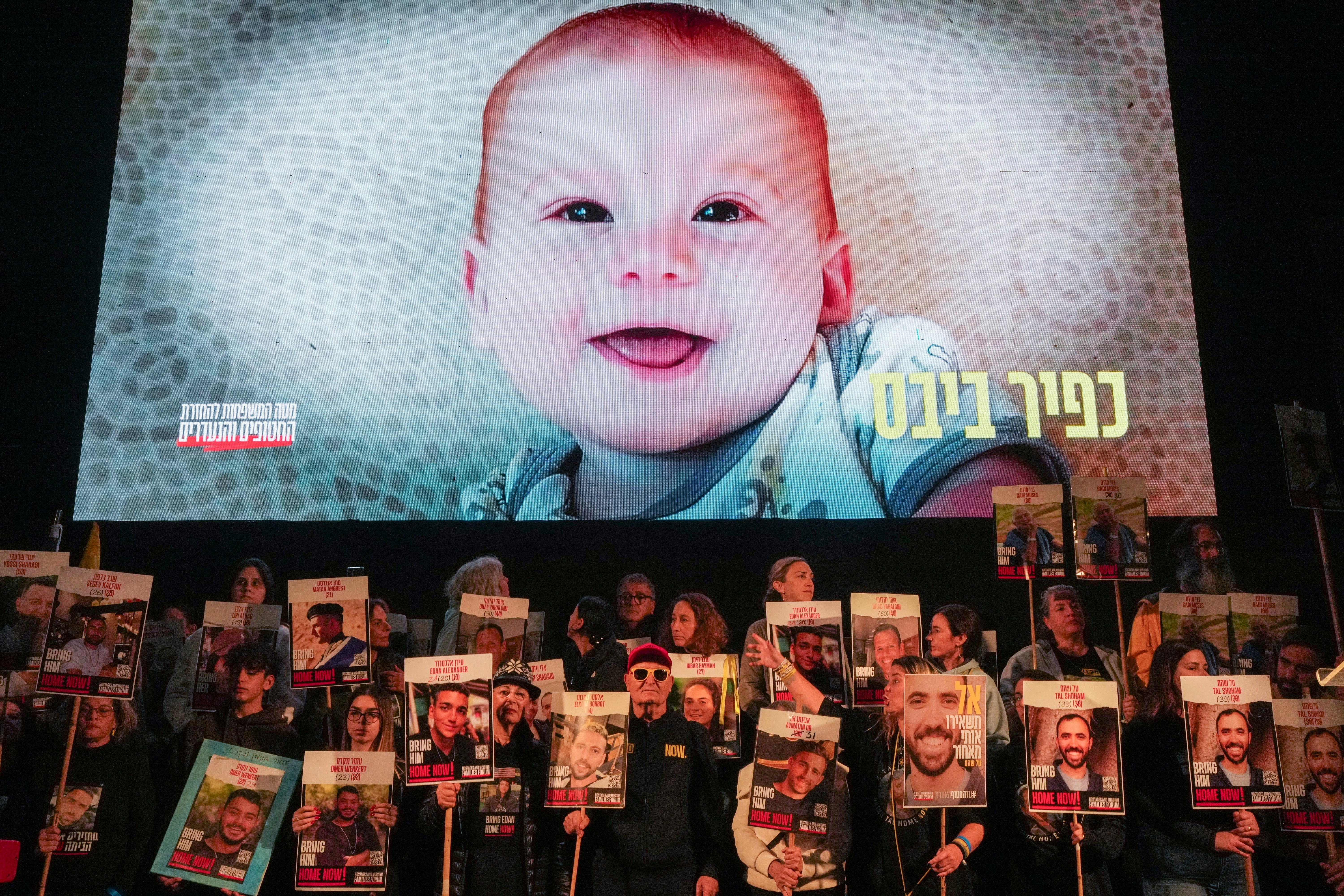 Demonstrators hold portraits of hostages held by Hamas in the Gaza Strip as a video featuring Kfir Bibas, who, along with his parents Shiri and Yarden Bibas, and his brother Ariel, is still being held hostage in Gaza