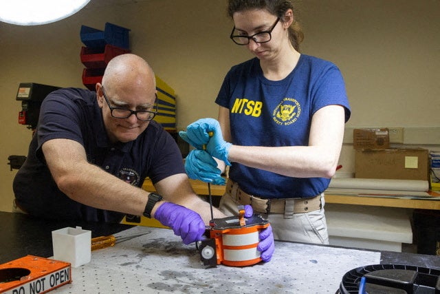 NTSB investigators work on the black box of American Eagle flight 5342, which was involved in a collision with a Black Hawk helicopter last Wednesday