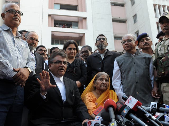 <p>Indian widow Zakia Jafri looks on as lawyer Mihir Desai (C/L) addresses media representatives outside a court in Ahmedabad on 26 December 2013</p>