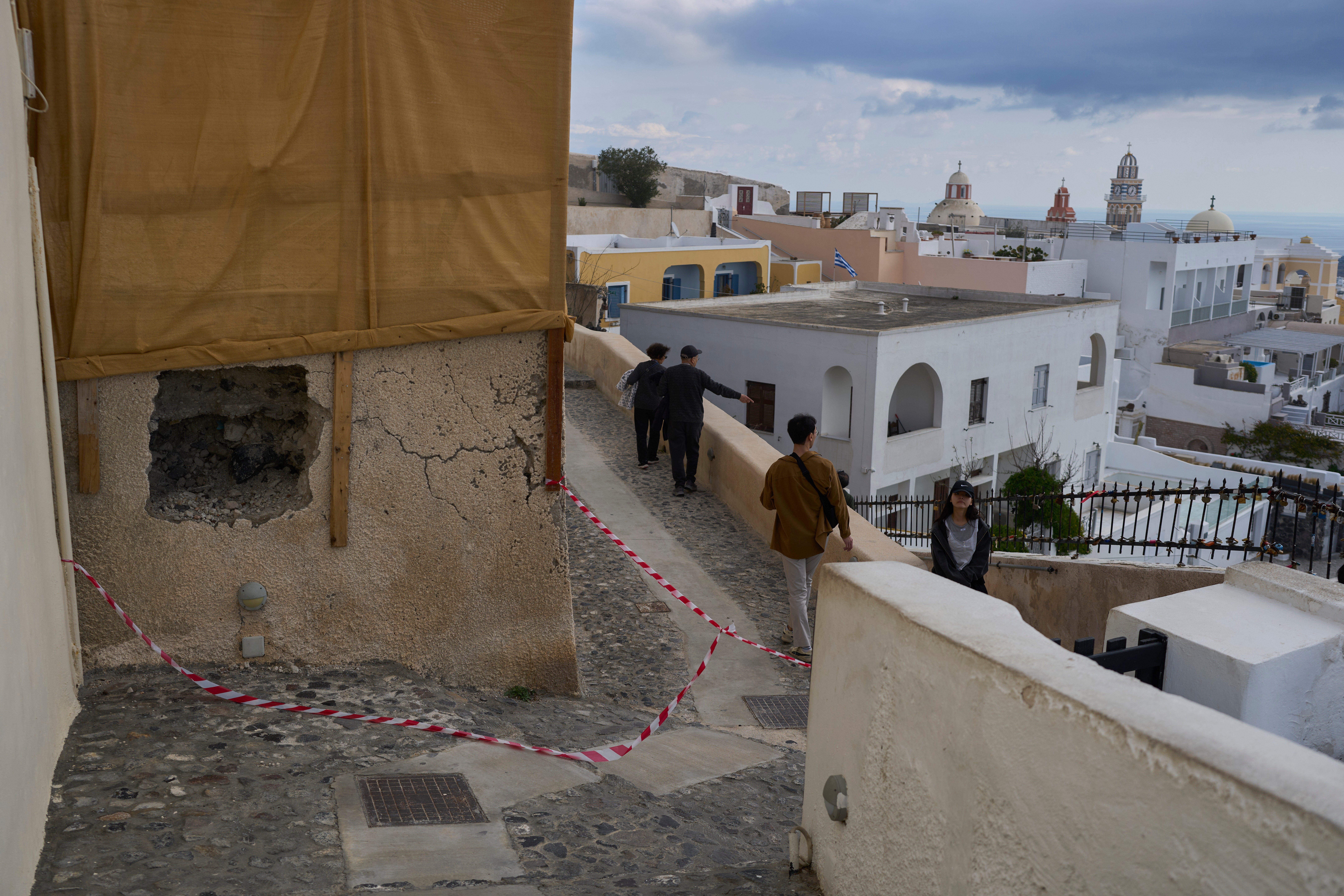 Tourists walk on the narrow streets of Fira town as emergency crews were deployed after an earthquake swarm worries Greece