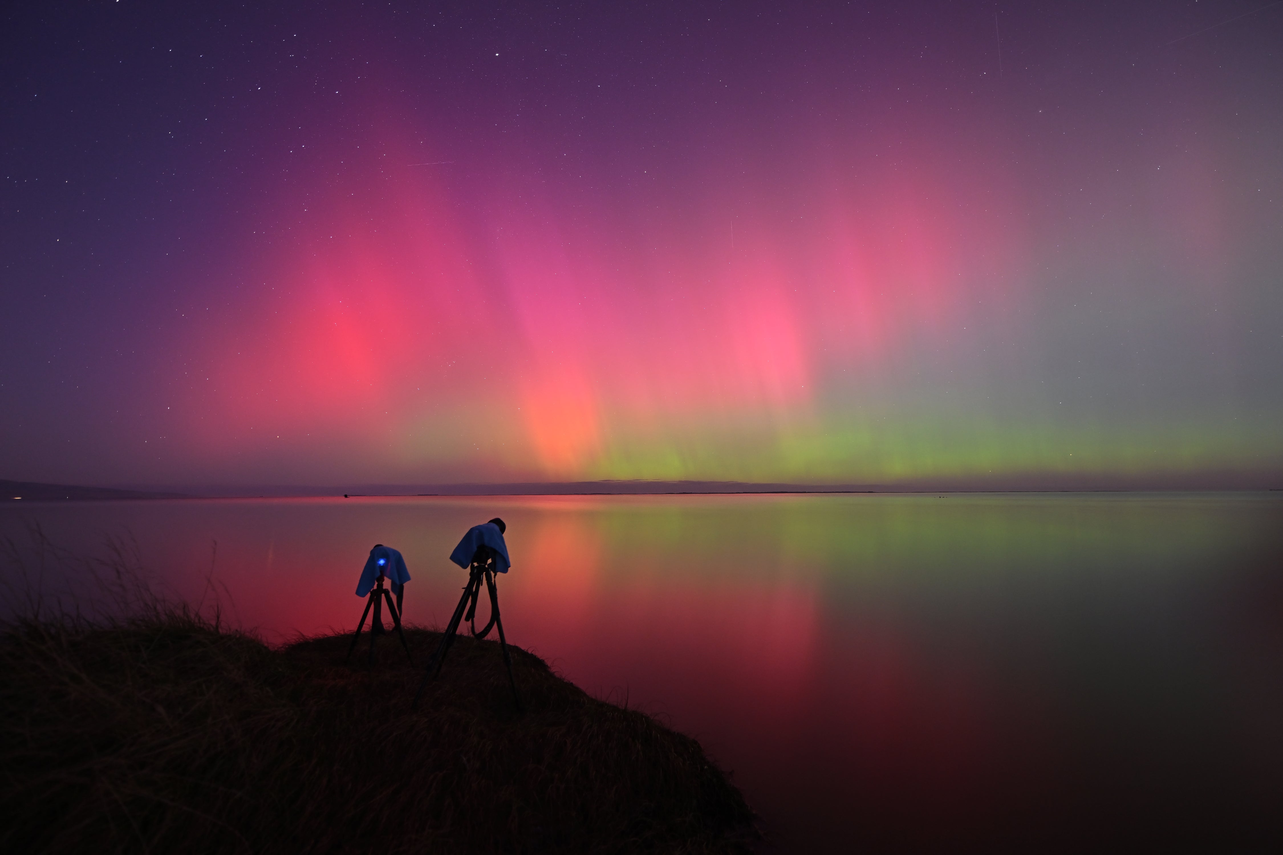 Aurora Australis, also known as the Southern Lights, glow on the horizon over Lake Ellesmere on the outskirts of Christchurch on 11 May 2024