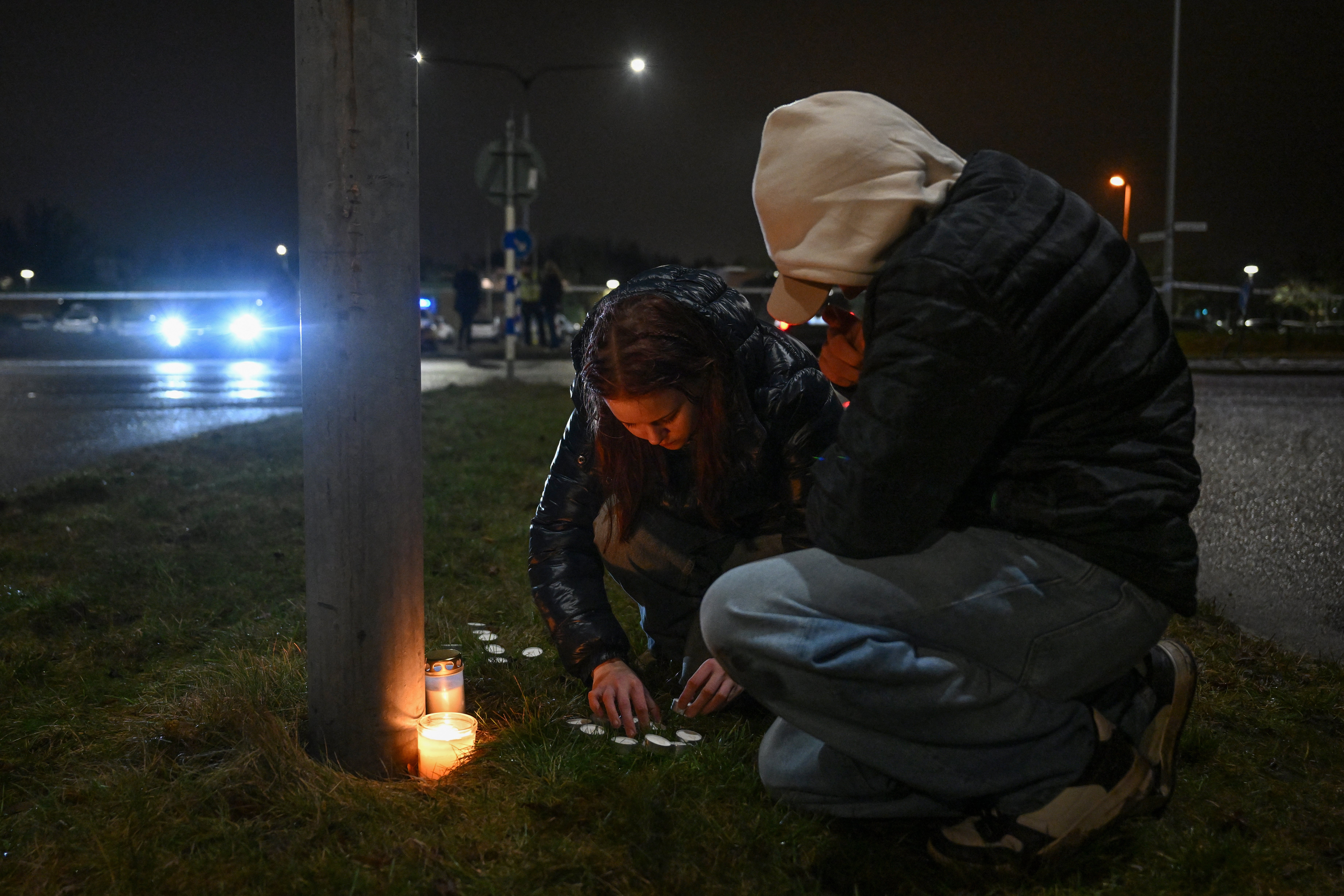 People light candles at a makeshift vigil