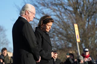 Sweden's King Carl XVI Gustaf and Queen Silvia place flowers at a memorial near the scene of a shooting