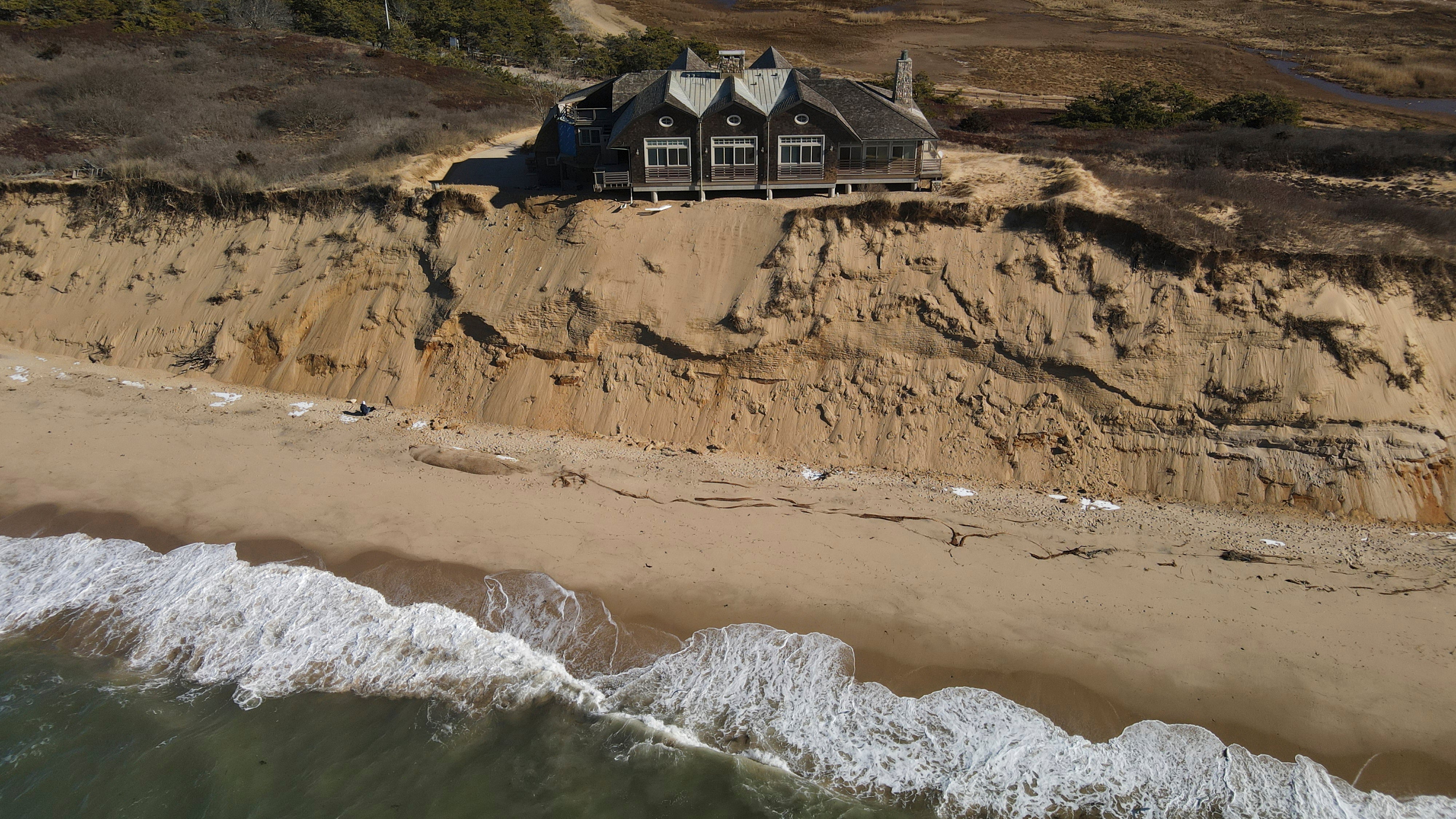 A house sits on a chunk of sand overlooking the beach in Wellfleet